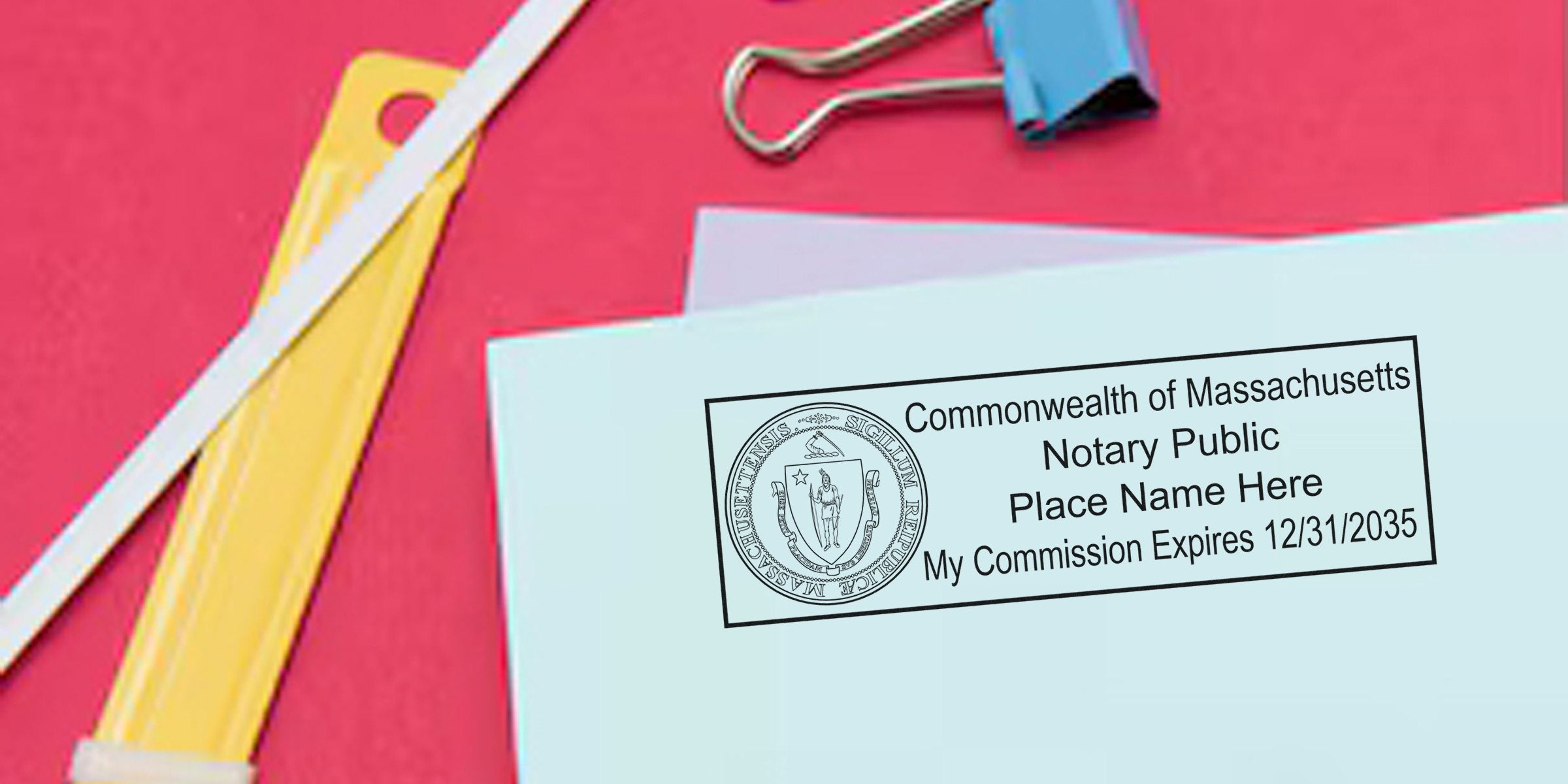 Massachusetts notary public stamp on blue paper with commission expiration date, surrounded by office supplies, showing how to become a notary in Massachusetts.
