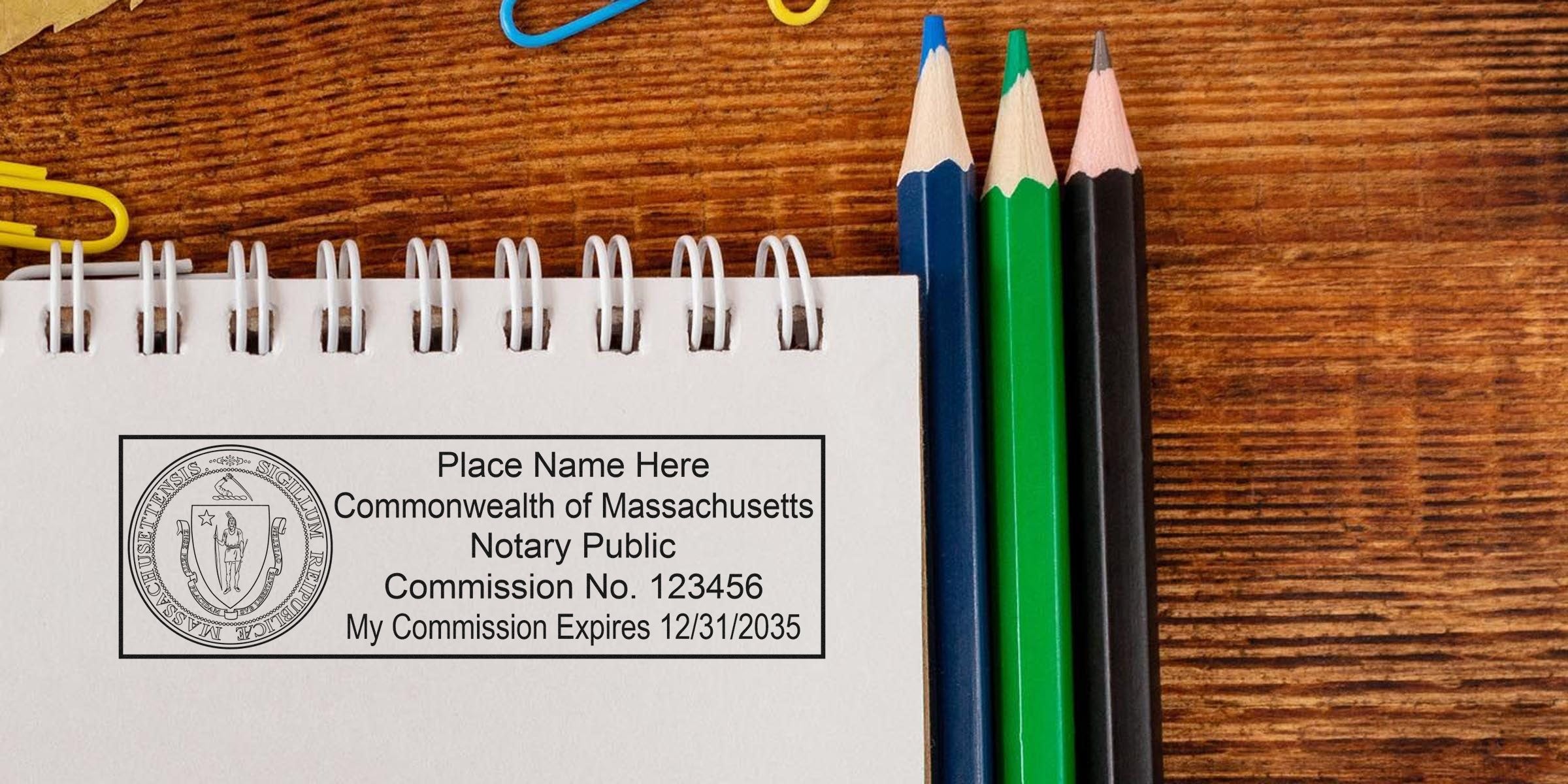 MA notary stamp on notebook with colored pencils on wooden desk, showcasing the top Massachusetts notary stamp.