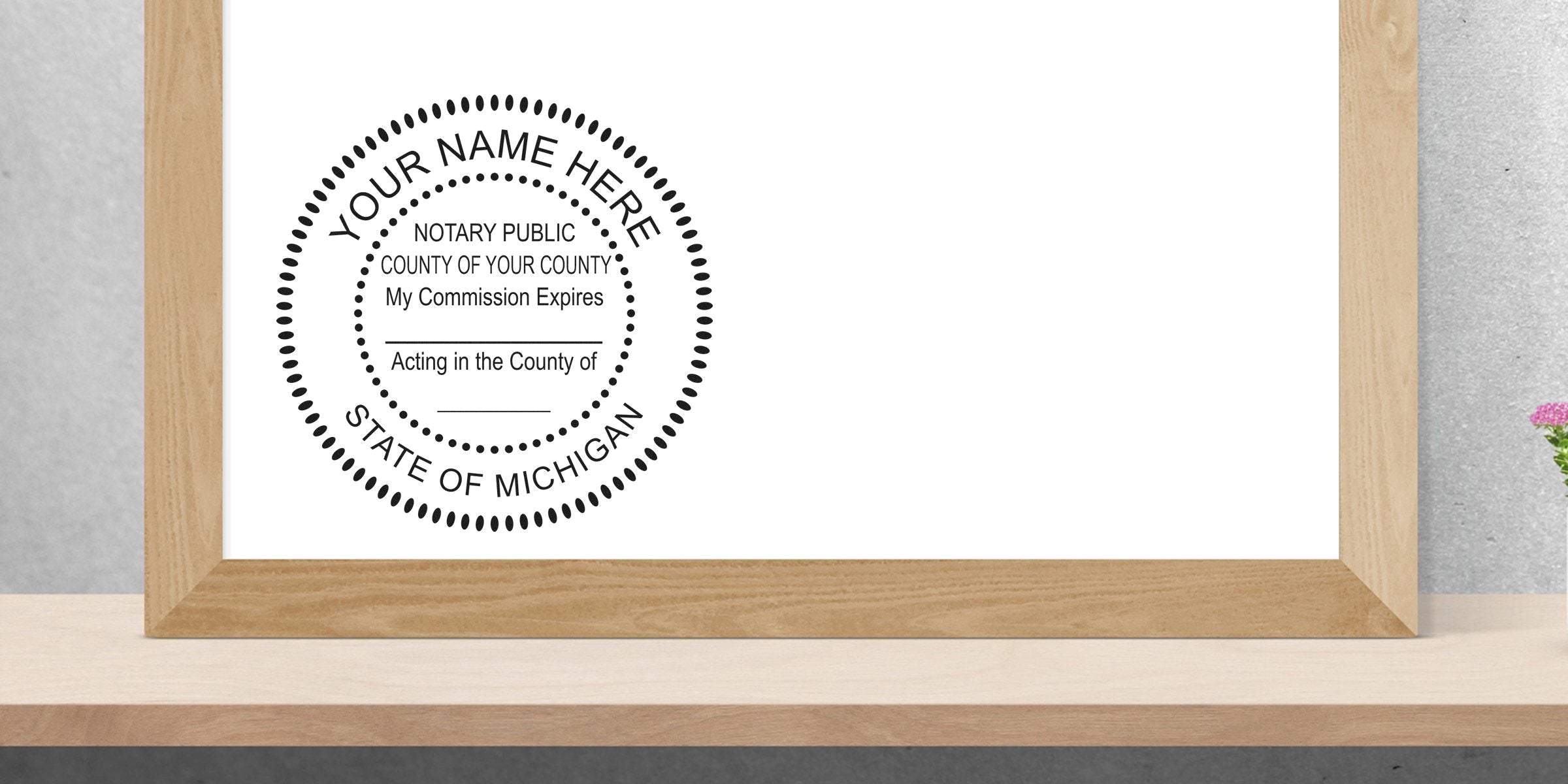 Custom Michigan notary stamp with commission expiration and county info in wooden frame on desk, surrounded by essential Michigan notary supplies and tools.