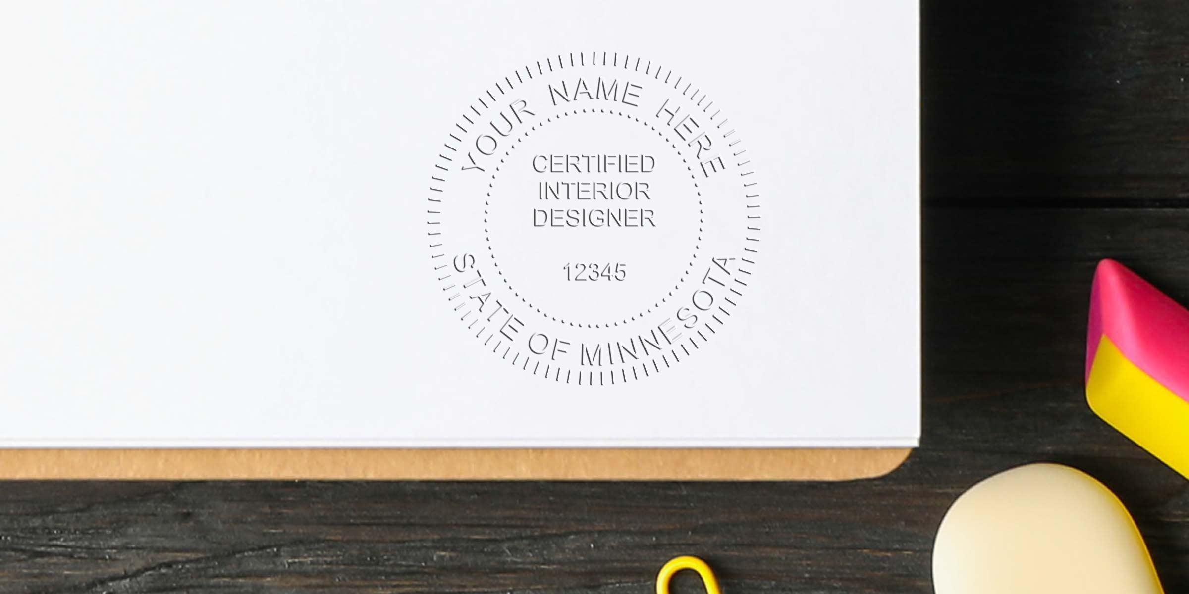 Minnesota interior designer stamp on white paper with office supplies on wooden desk, showing professional interior design license and Minnesota certification seal.