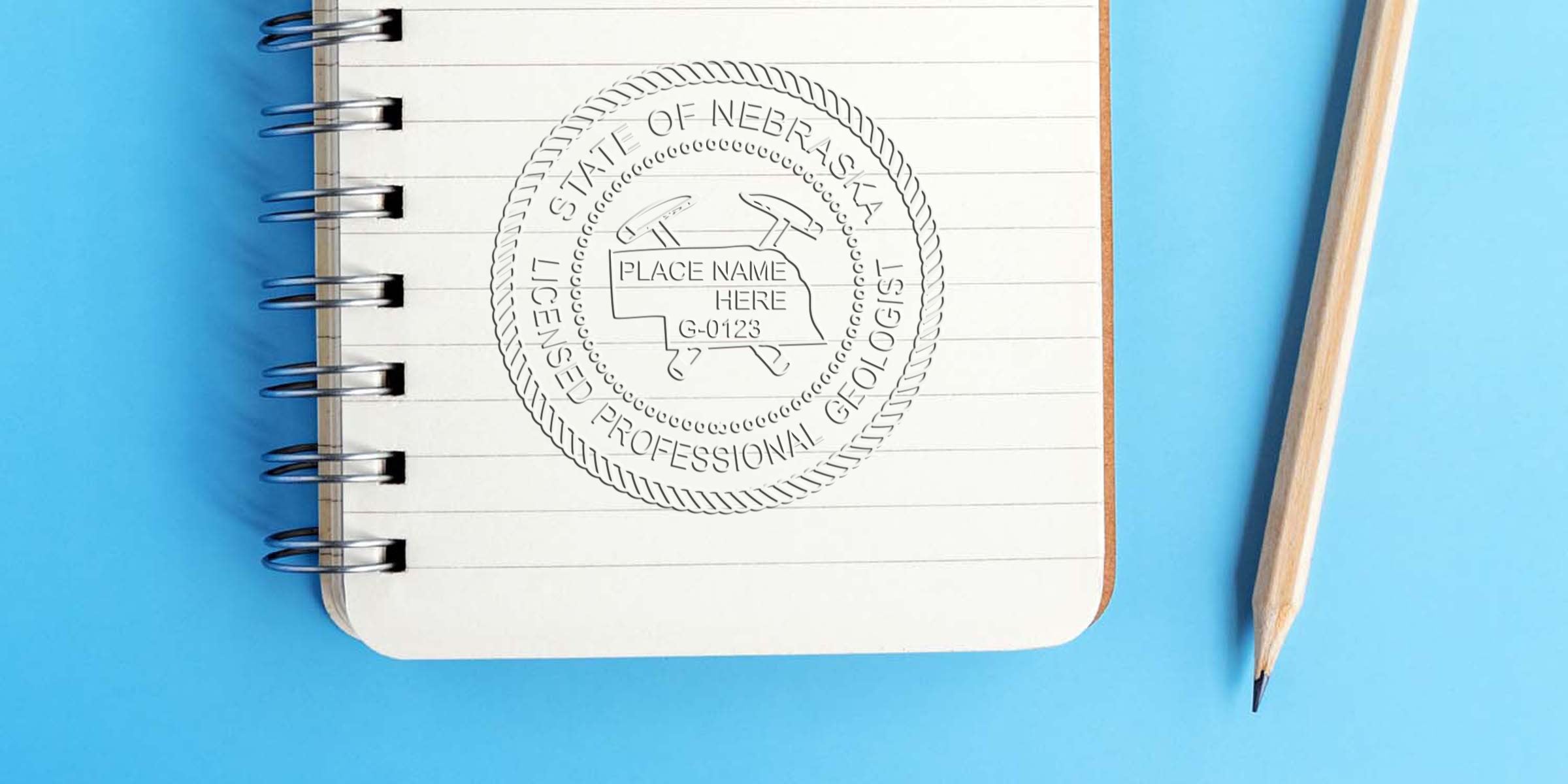 Nebraska Geologist Stamp on notebook with pencil, showing Nebraska licensed professional geologist certification seal on blue background.