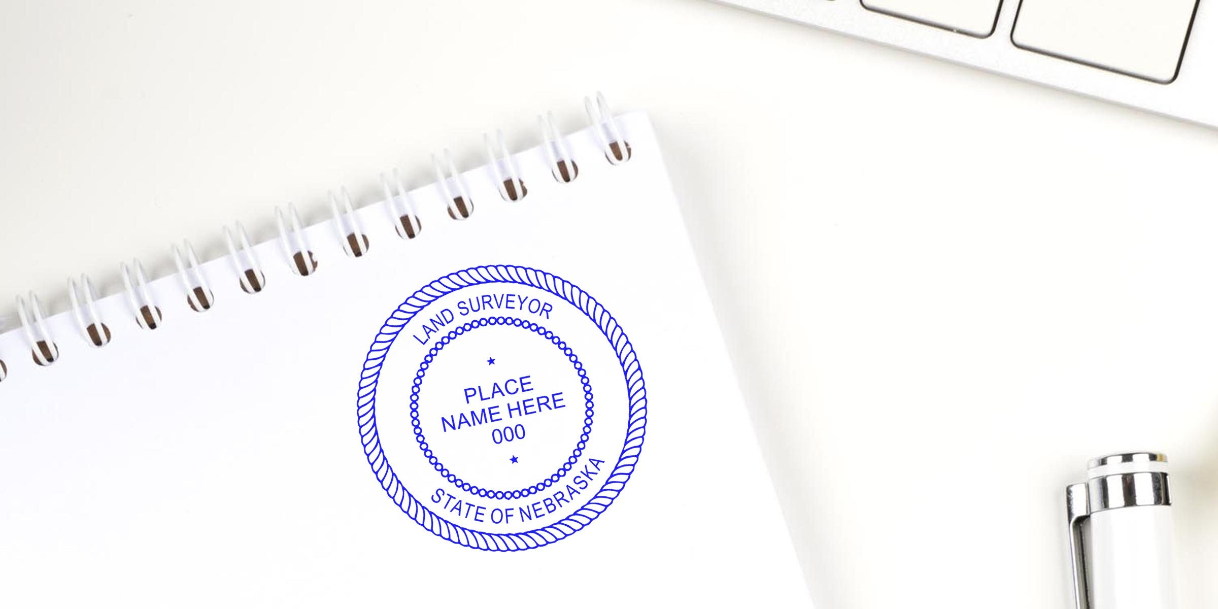 Custom Nebraska land surveyor stamp on white notepad by keyboard and pen, meeting all design requirements.