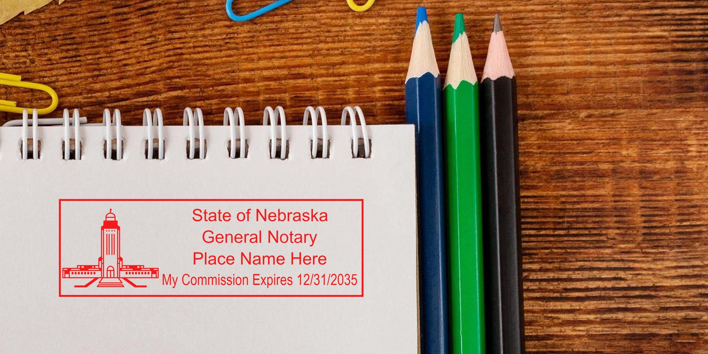 Nebraska notary stamp on notebook with colored pencils on wooden desk, part of Nebraska notary kit and supplies.