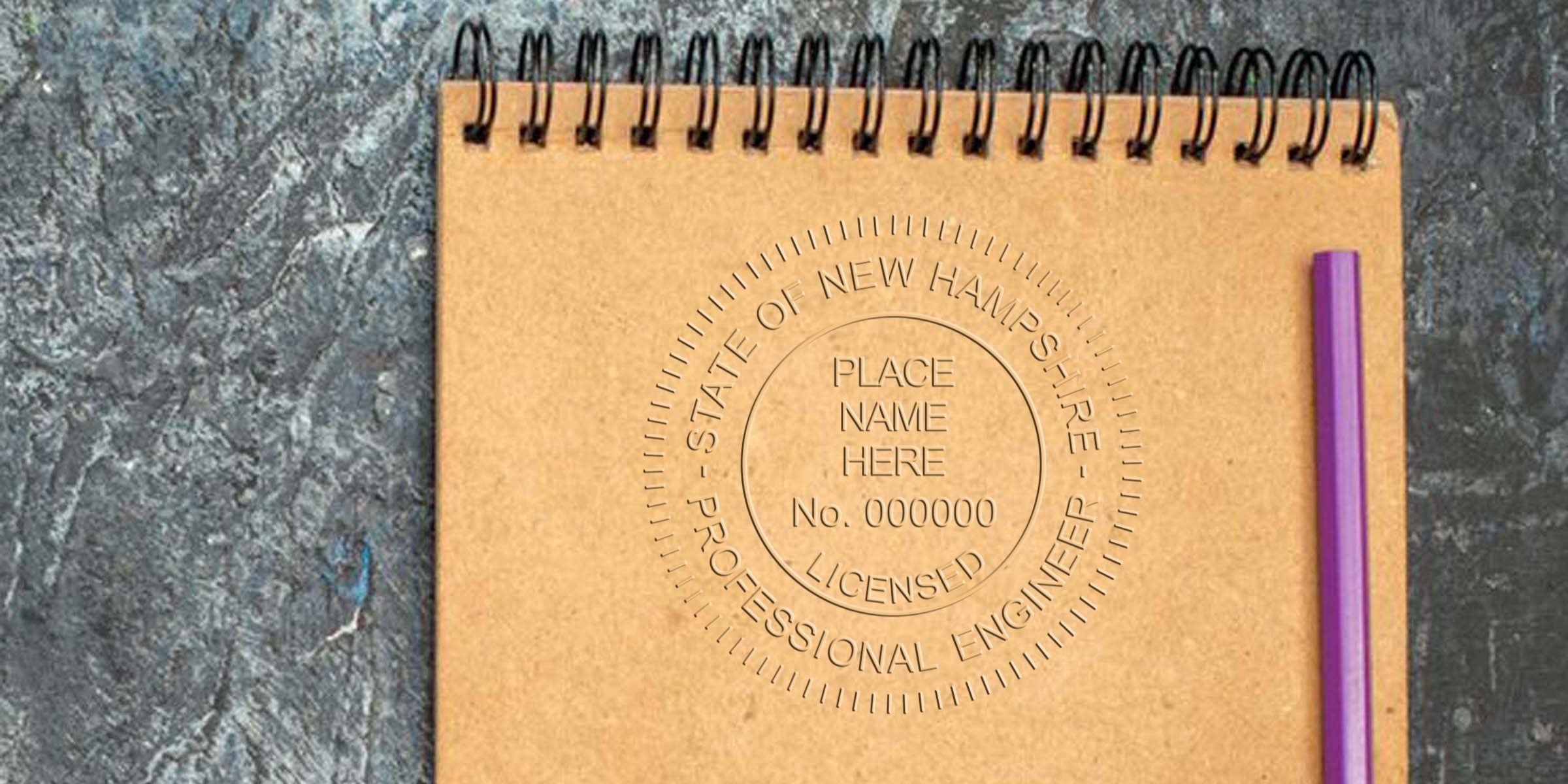 Professional Engineer stamp on notebook with purple pen, showing New Hampshire Engineering License on textured surface.