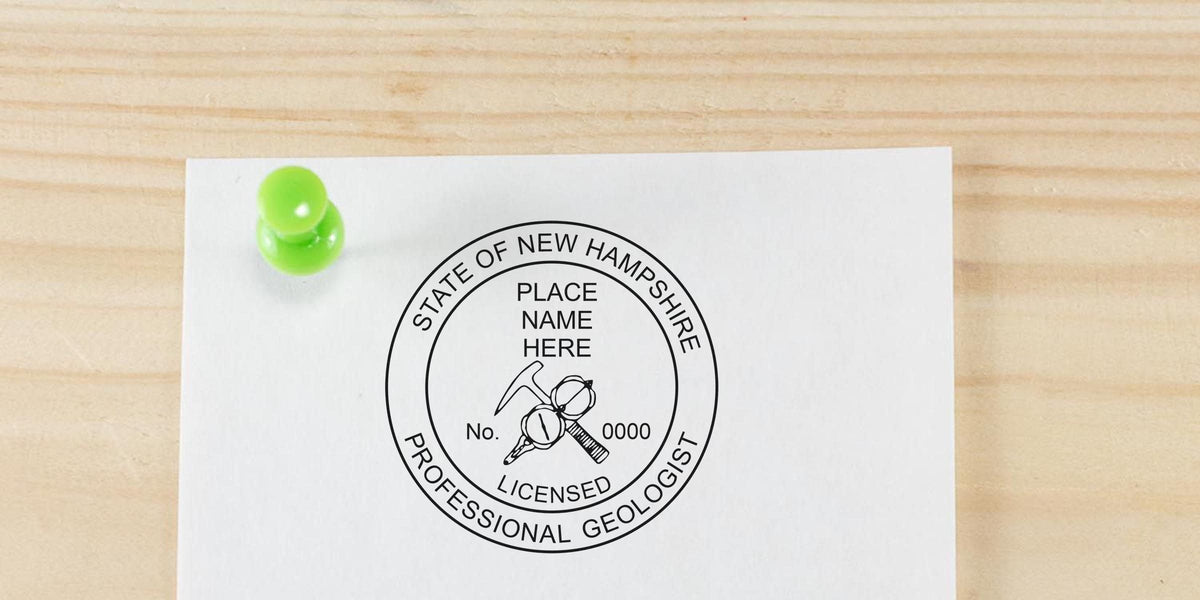 New Hampshire Professional Geologist Stamp with green push pin on wooden background highlighting licensing requirements.