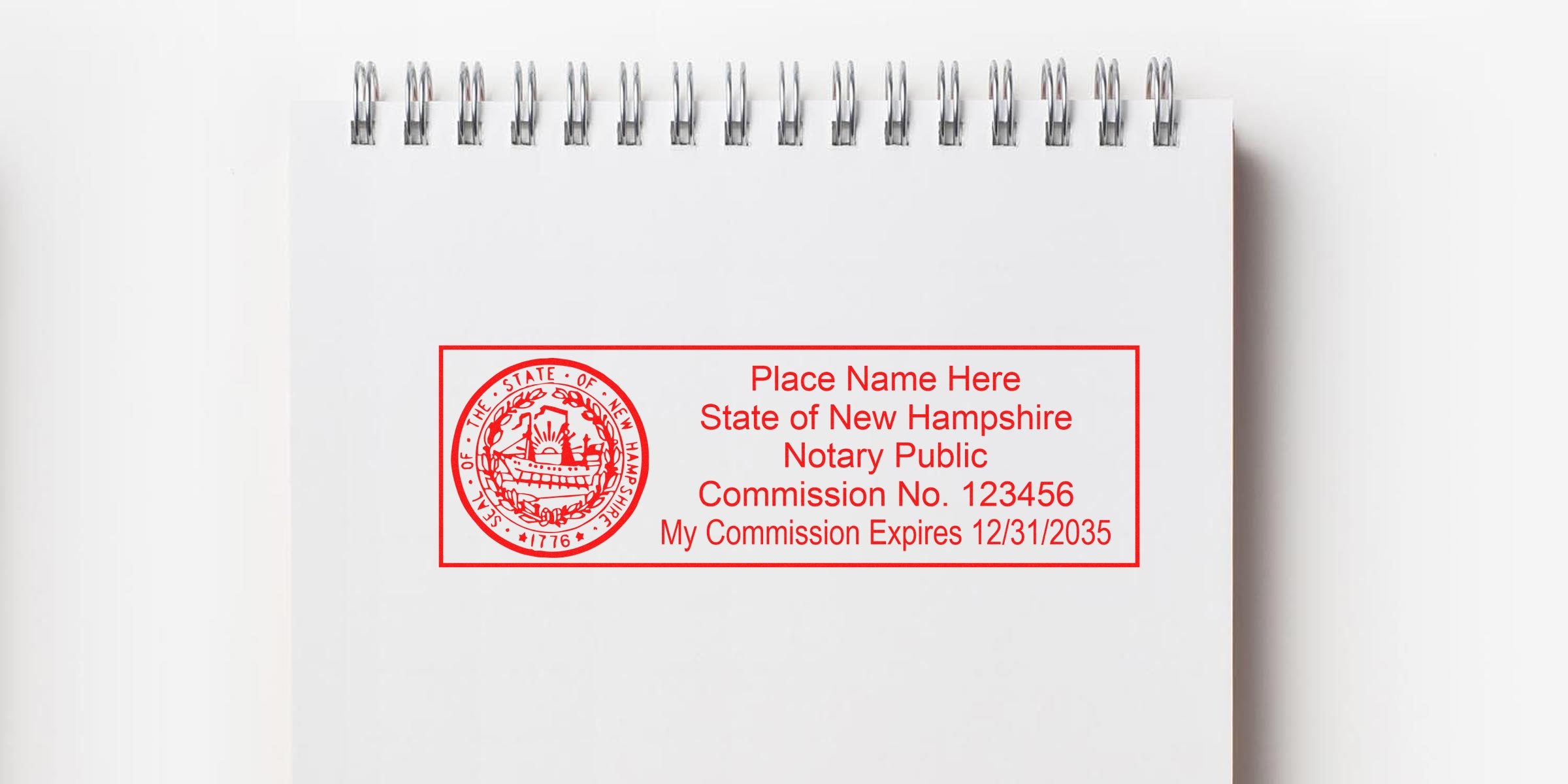 Red New Hampshire notary stamp with commission number and expiration date on white spiral notebook, showcasing New Hampshire notary supplies and deals.