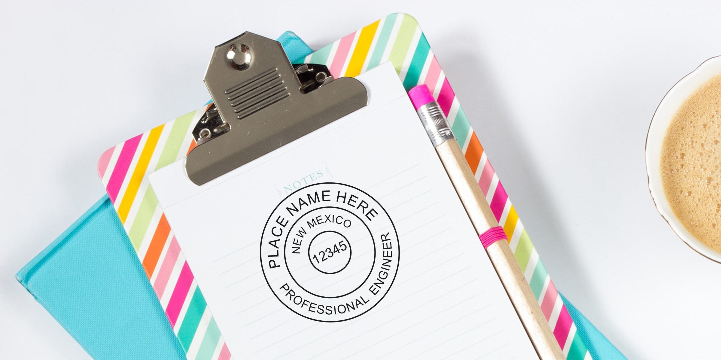 New Mexico PE seal stamped on clipboard with colorful stripes and pencil, displayed on office desk alongside coffee cup.