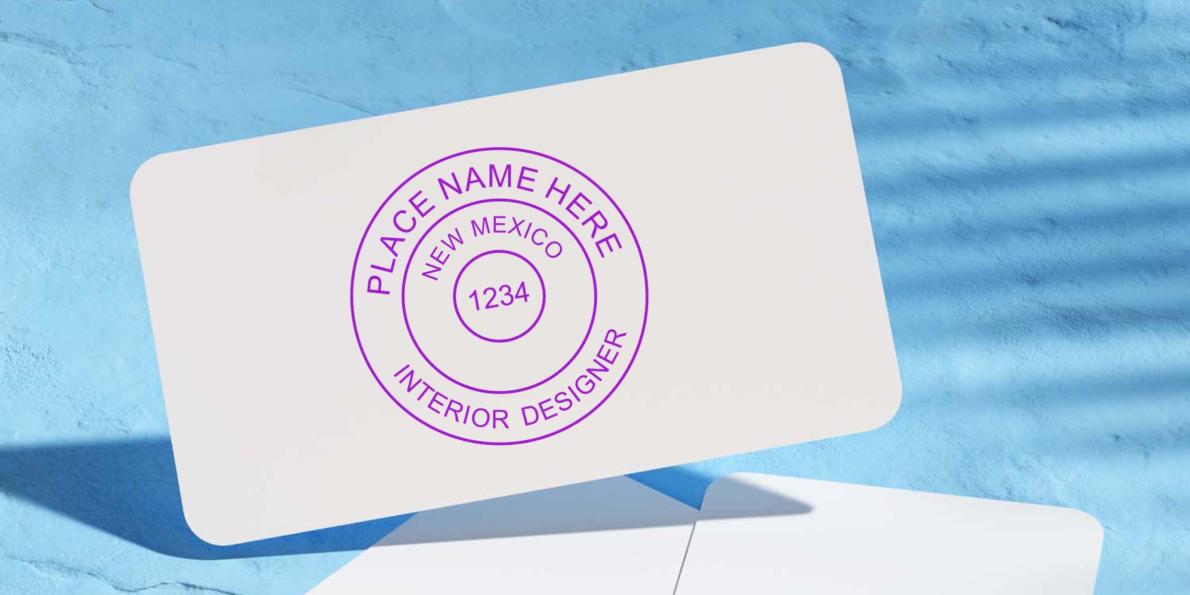 New Mexico interior designer seal embossed on white business card with blue textured background, highlighting NM interior design certification.