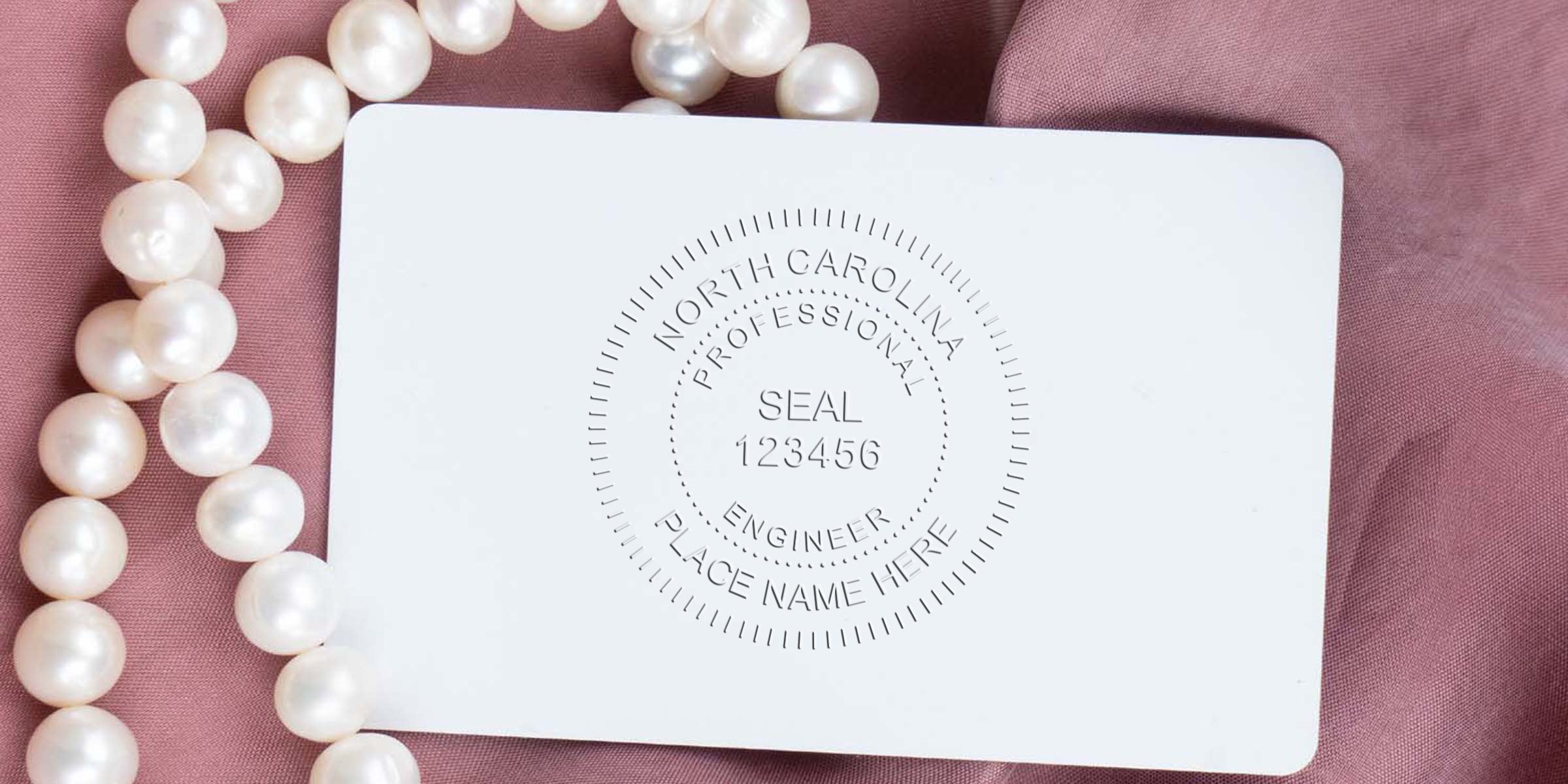 North Carolina PE stamp embossed on white card with pearl necklace on pink fabric, highlighting online PE stamp purchase option.