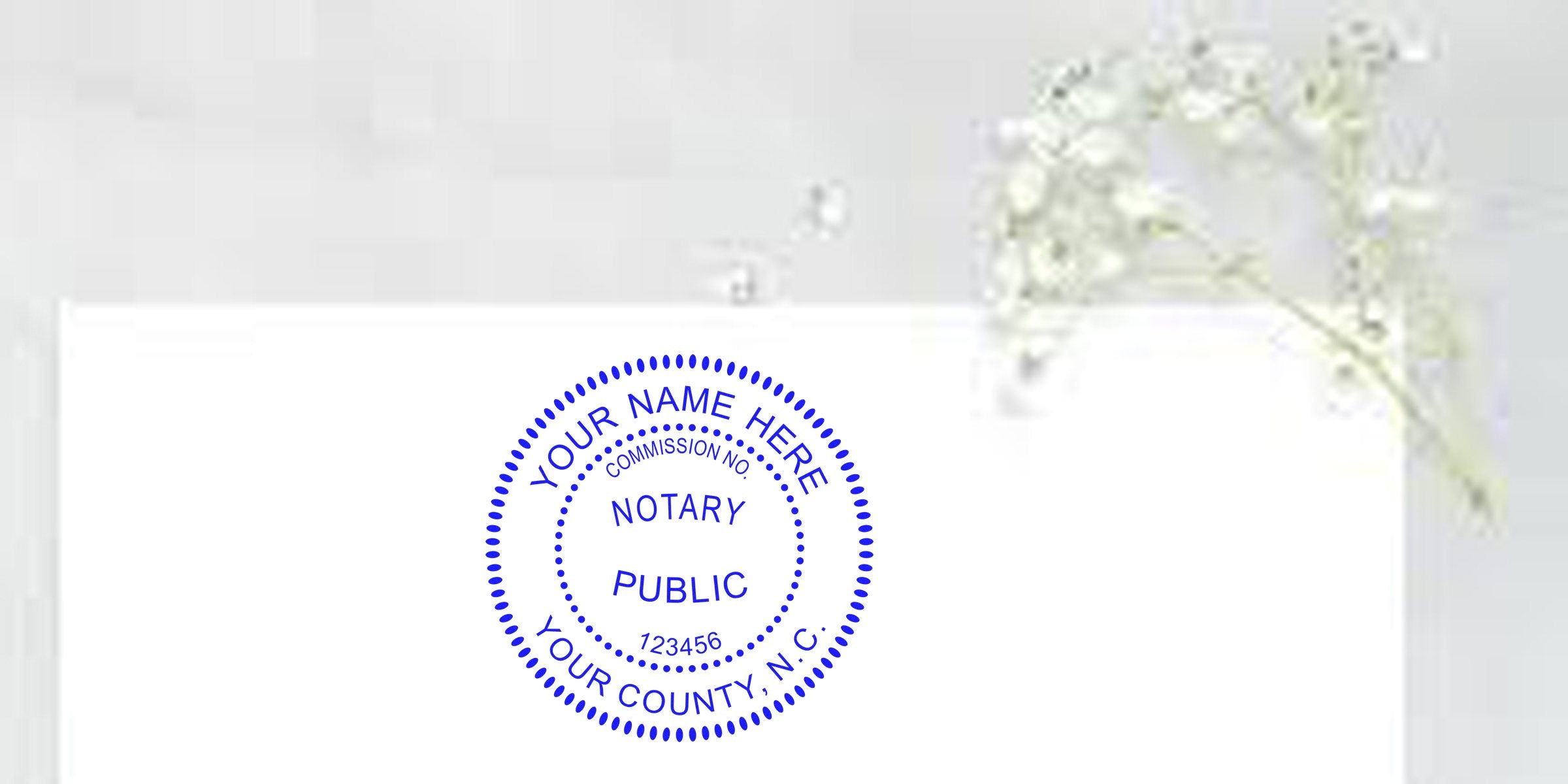 NC notary stamp in blue ink on white paper with a floral background, showcasing top notary supplies.
