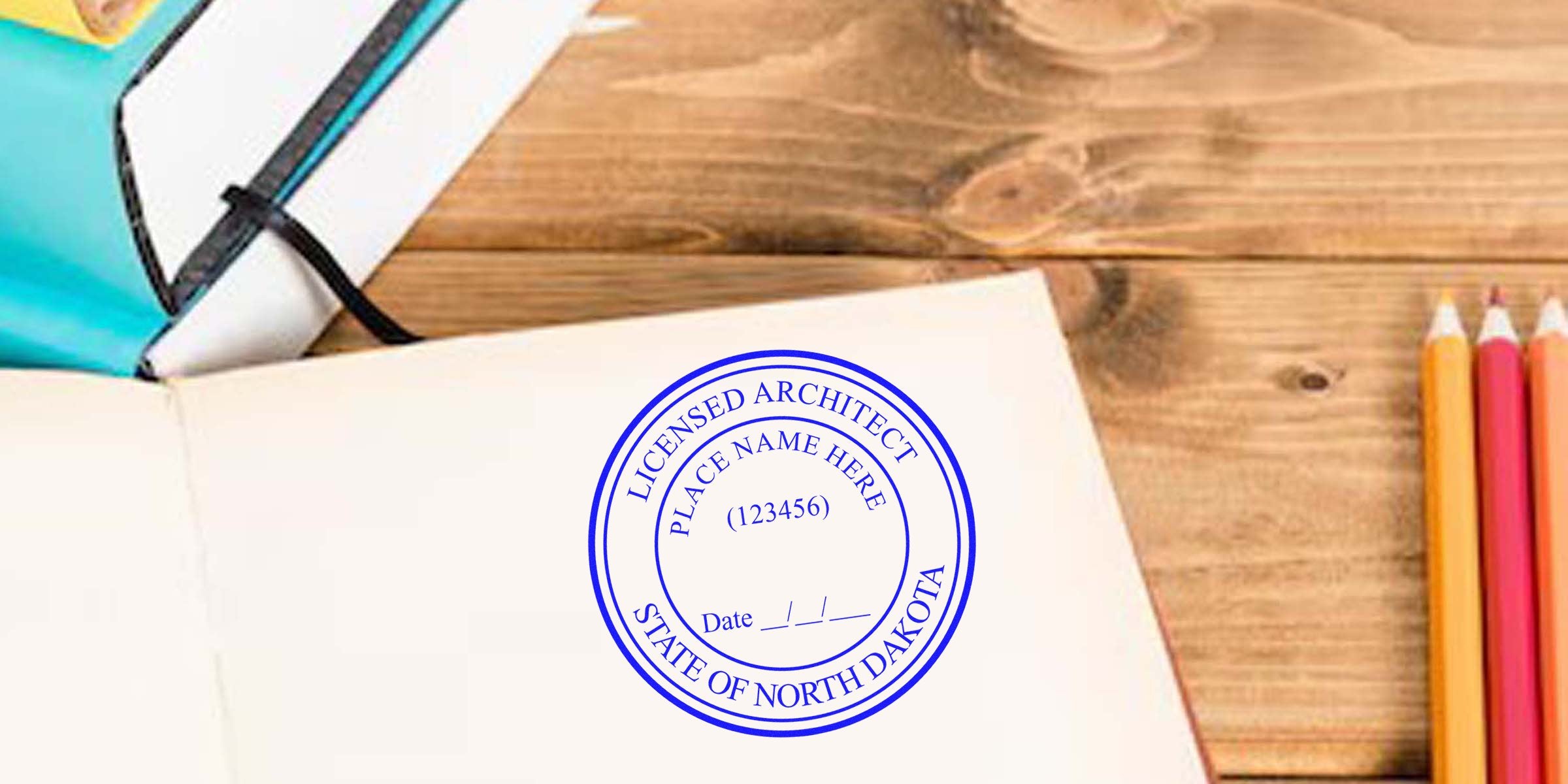 North Dakota architect stamp on open notebook with colored pencils and planner on wooden desk, symbolizing professional architectural design.