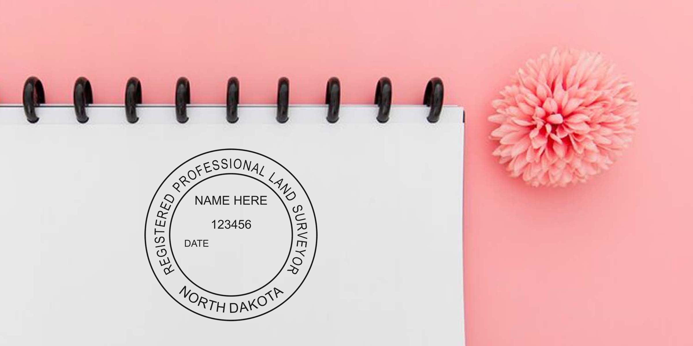 Registered North Dakota surveyor stamp on white notepad with pink flower background, showing the surveyor stamp and tips for stamp replacement.