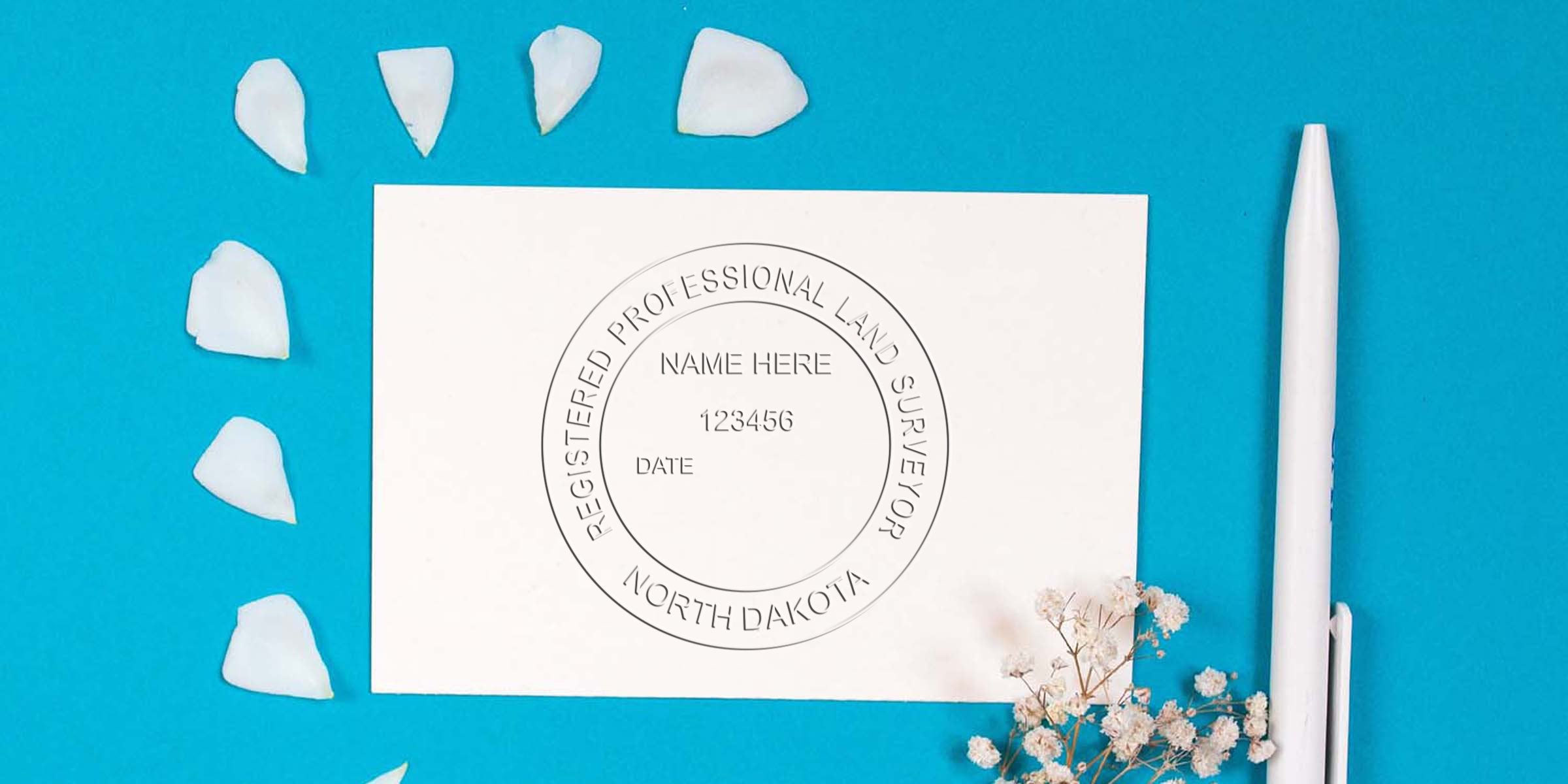 Registered professional land surveyor seal embossed on white card with white pen and flower petals on blue background, highlighting embossing seal details.