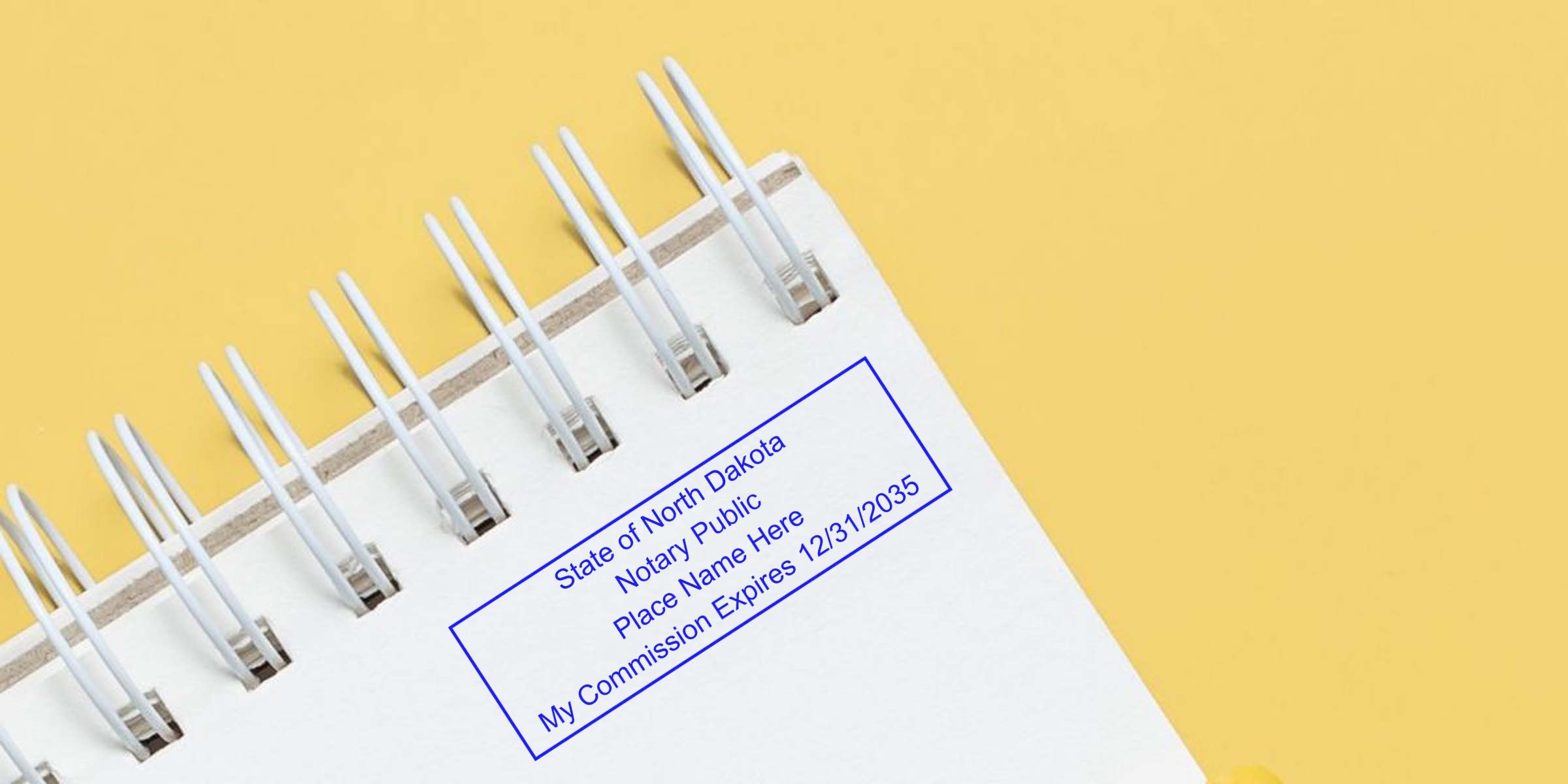 Spiral notebook with North Dakota notary stamps on white paper, showing commission expiration date, affordable notary supplies on yellow background.