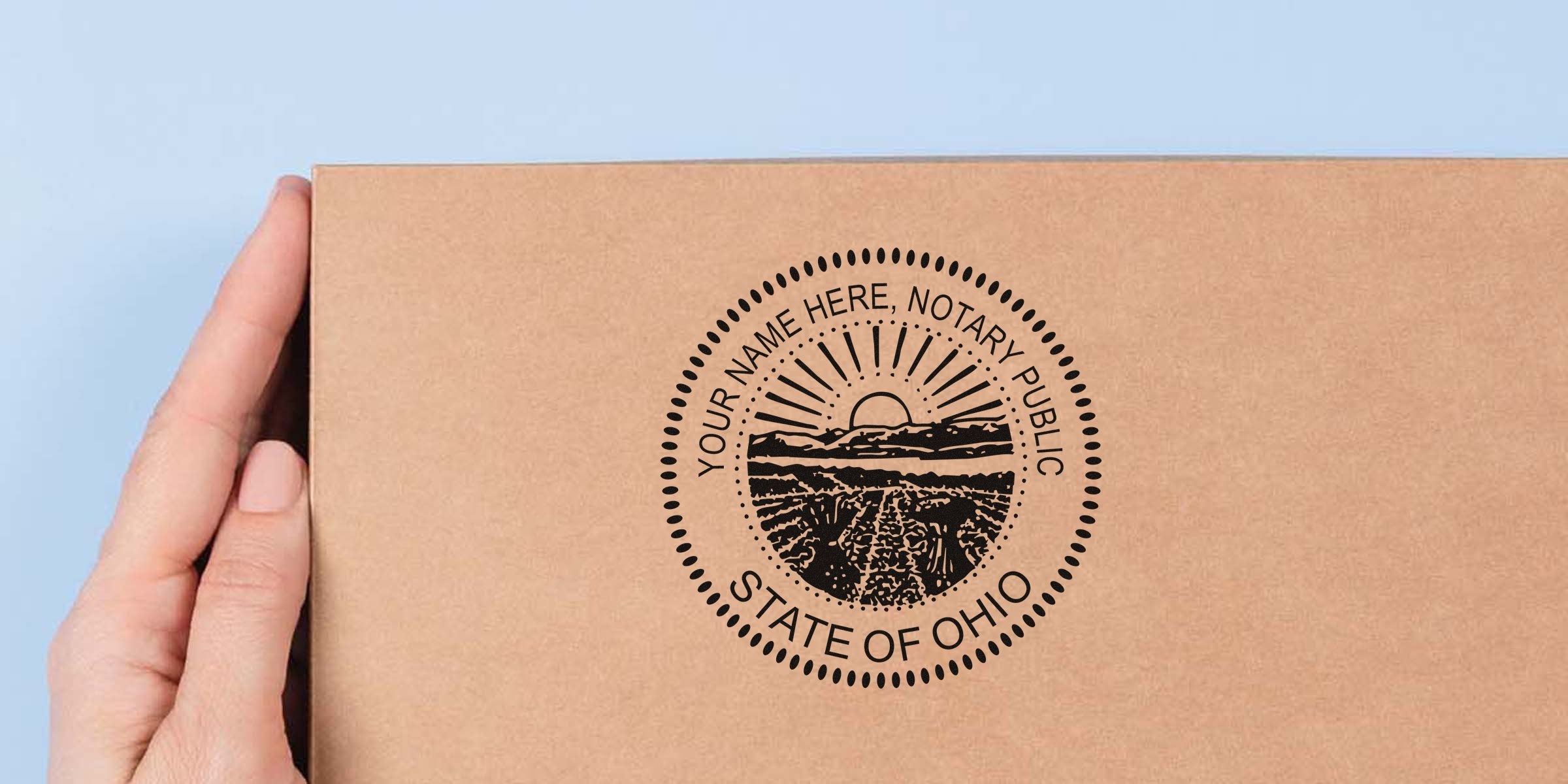 Hand holding a custom Ohio notary stamp on a cardboard box, featuring a personalized OH seal for official documents, perfect for choosing notary stamp options.