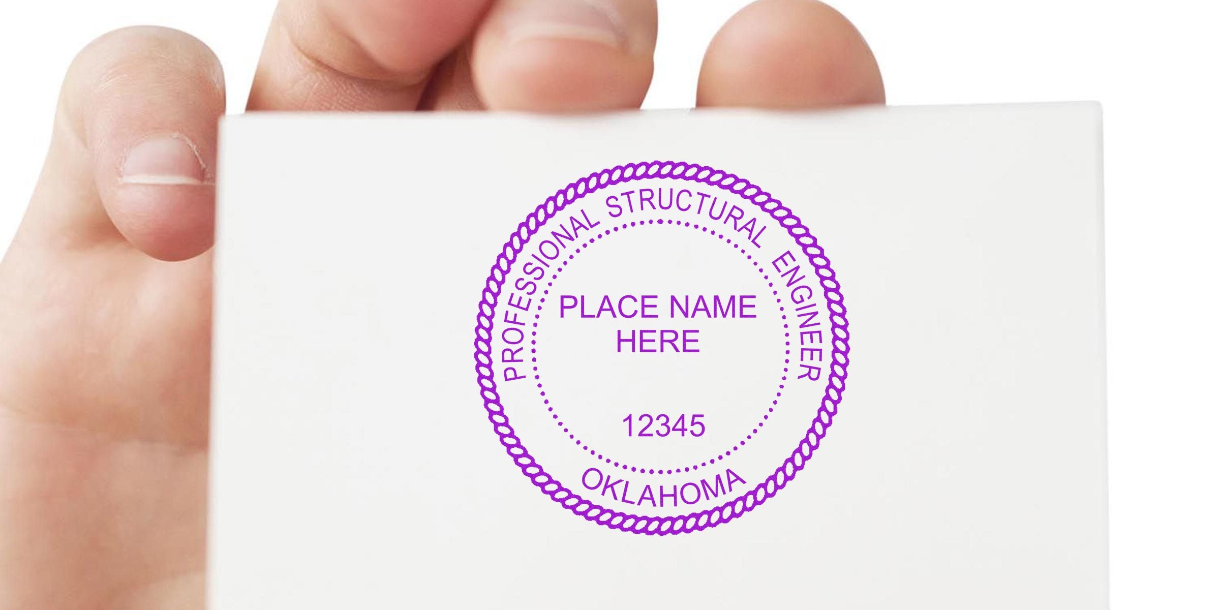 Hand holding white card with professional structural engineer stamp, Oklahoma seal, and license number, revealing engineering seal design details.