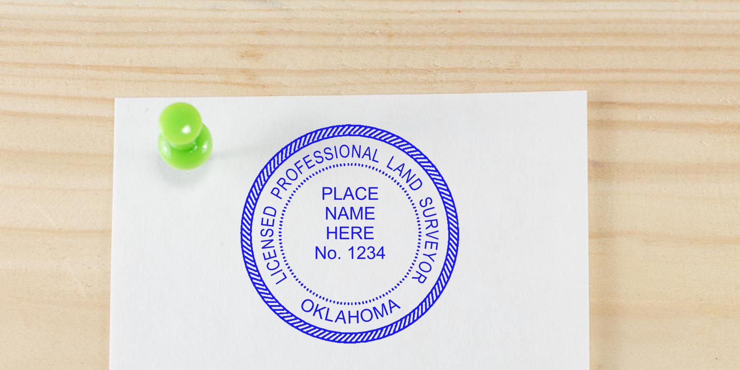 Oklahoma land surveyor stamp on white paper pinned with a green pushpin on a wooden surface, meeting all land surveyor stamp requirements.