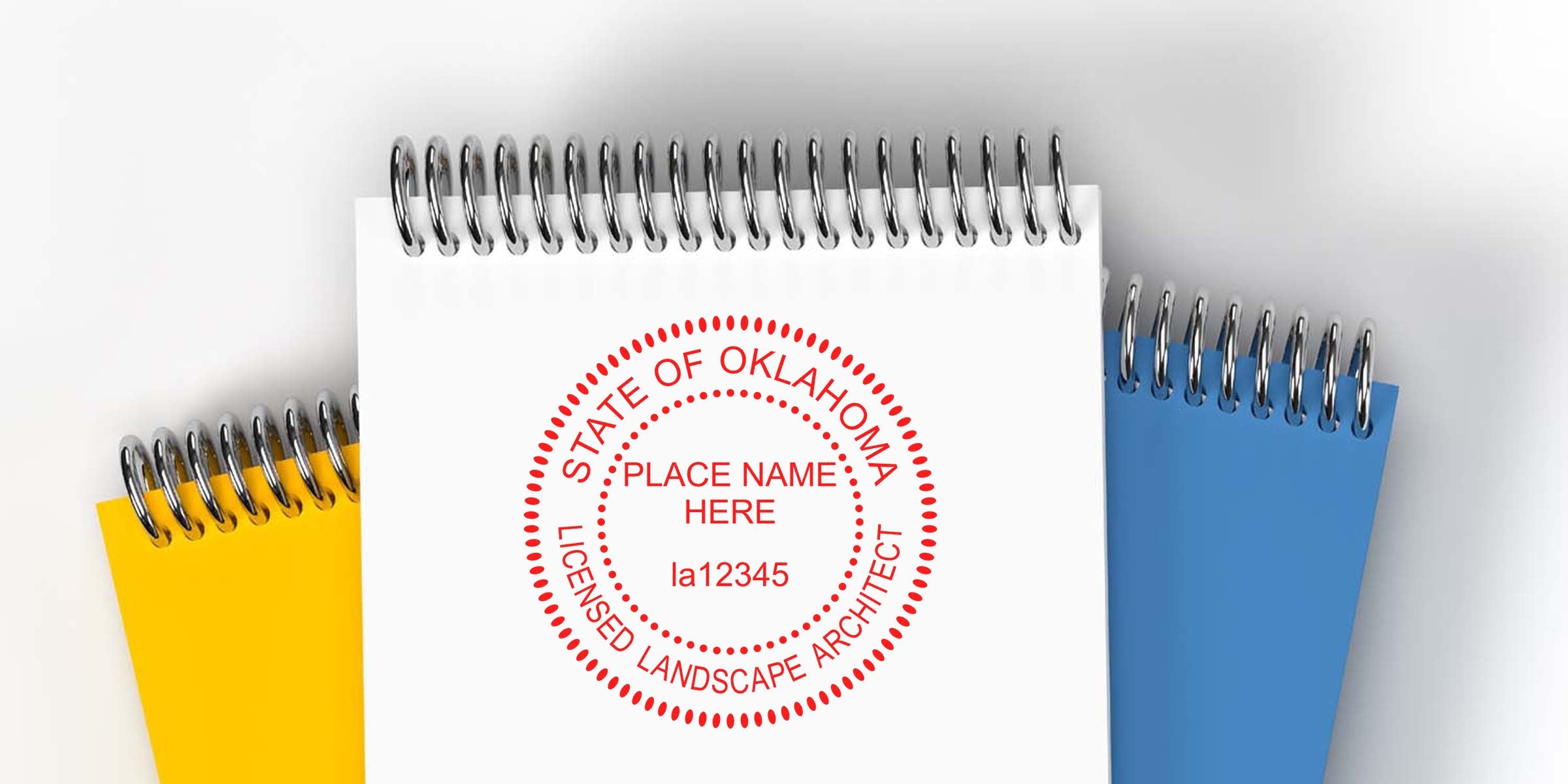Oklahoma licensed landscape architect stamp on white spiral notebook with yellow and blue notebooks in the background, highlighting Landscape Architect Stamp Renewal and Oklahoma License Renewal Tips.