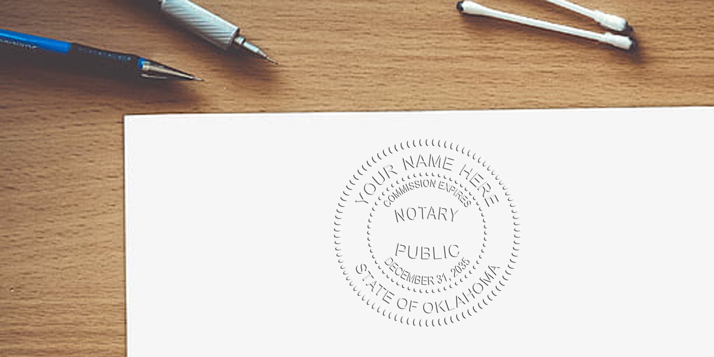 Oklahoma notary seals embossed on white paper with pens and cotton swabs on a wooden desk, showcasing the Oklahoma notary certification stamp and highlighting notary seal offers.