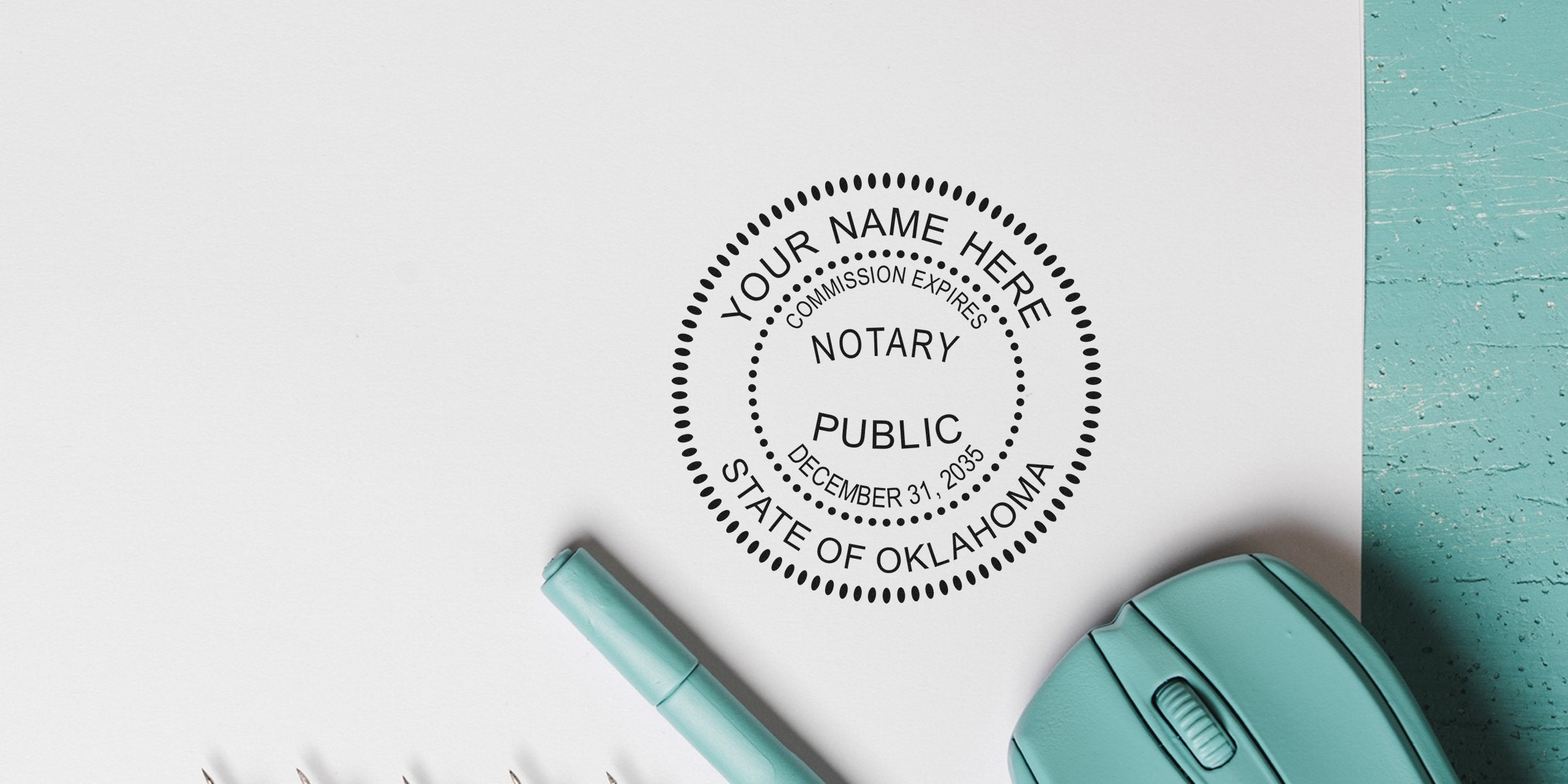 Oklahoma notary stamp with commission expiration date on white paper next to teal pen and computer mouse, showing Oklahoma notary requirements.