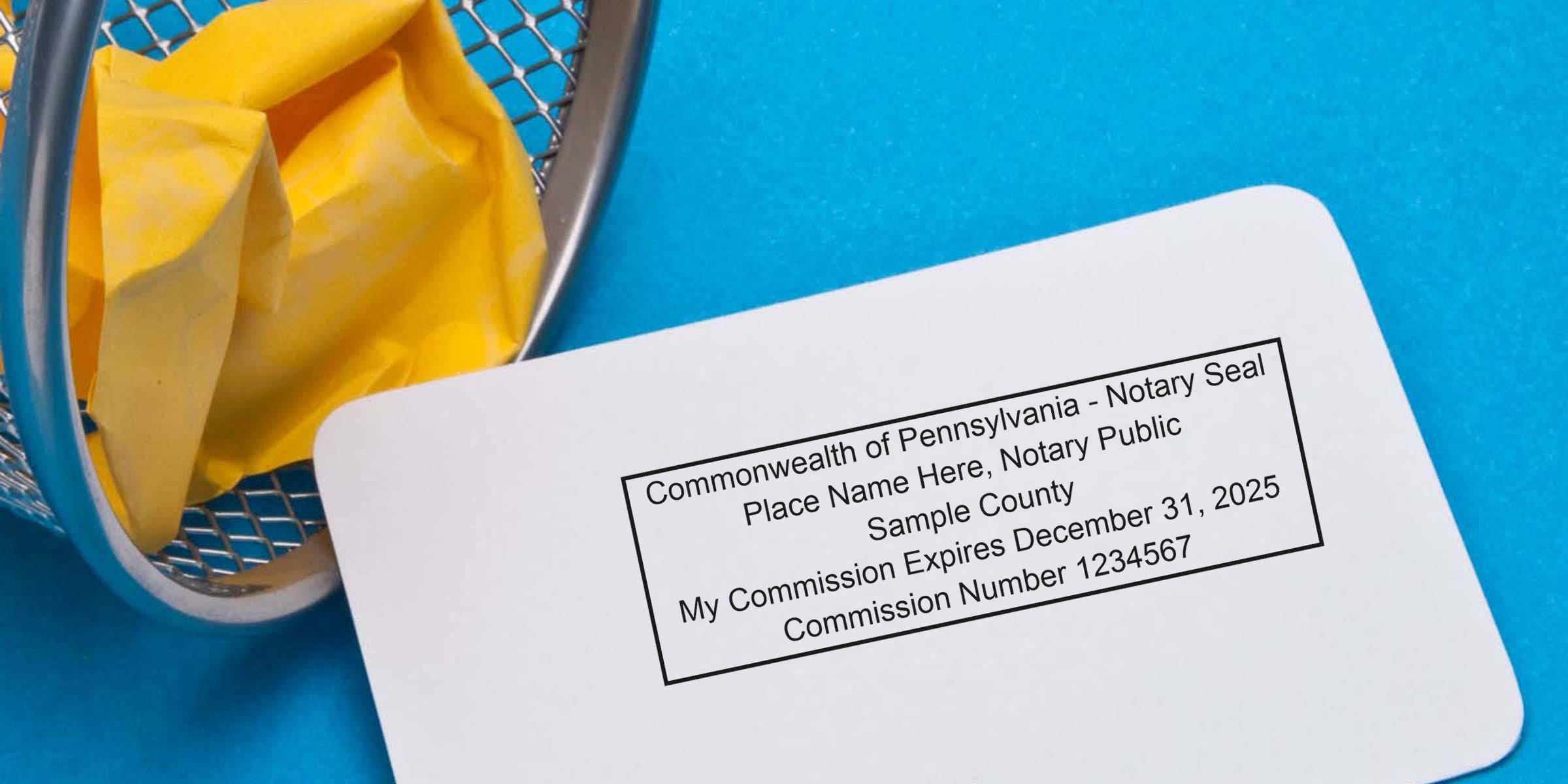 Sample Pennsylvania Notary Seal card with commission expiration and number on blue background beside yellow crumpled paper in trash bin, featured in Best Notary Seal Guide.