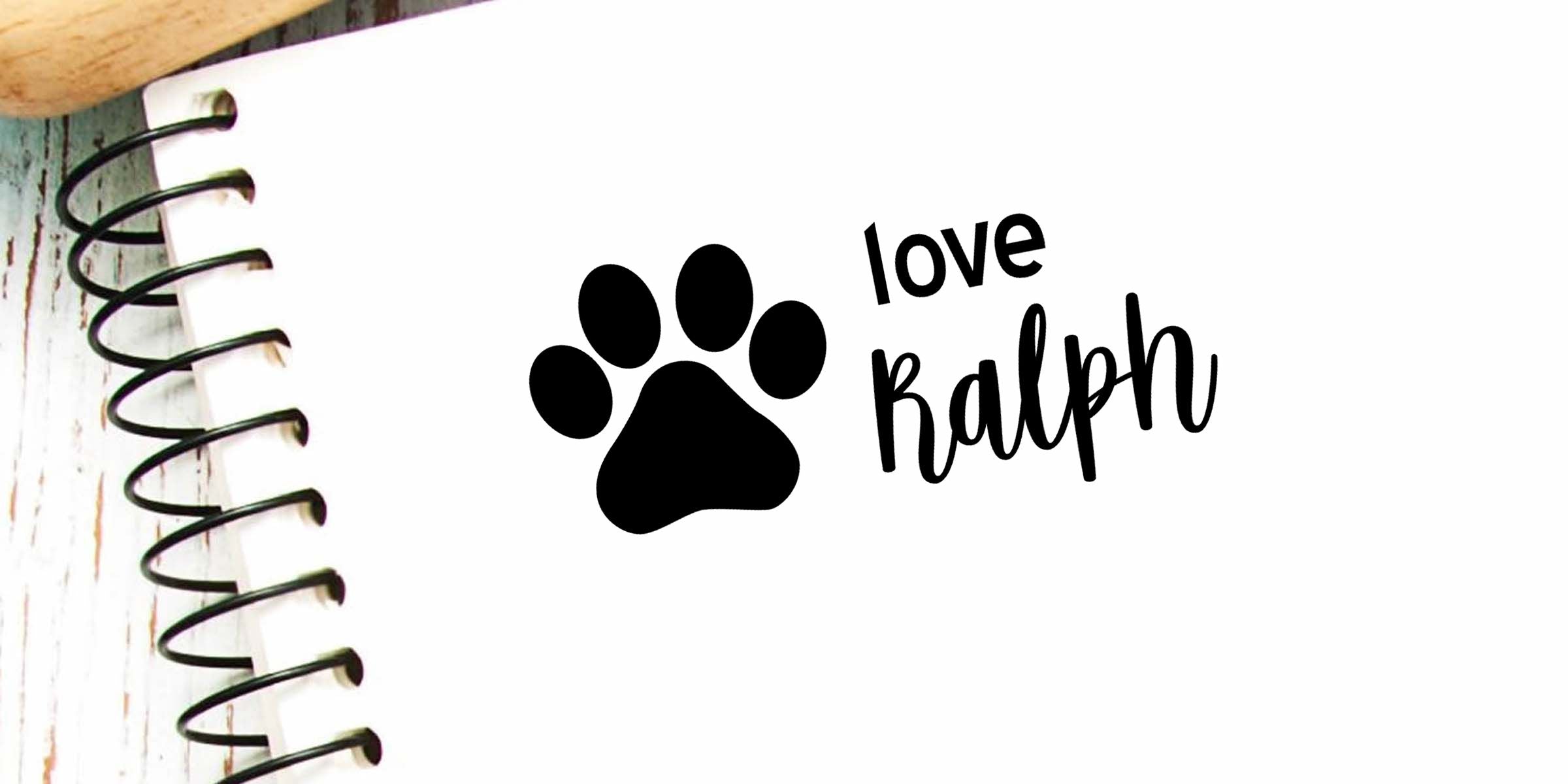 Black paw print with the words “love Ralph” on a spiral-bound notebook page