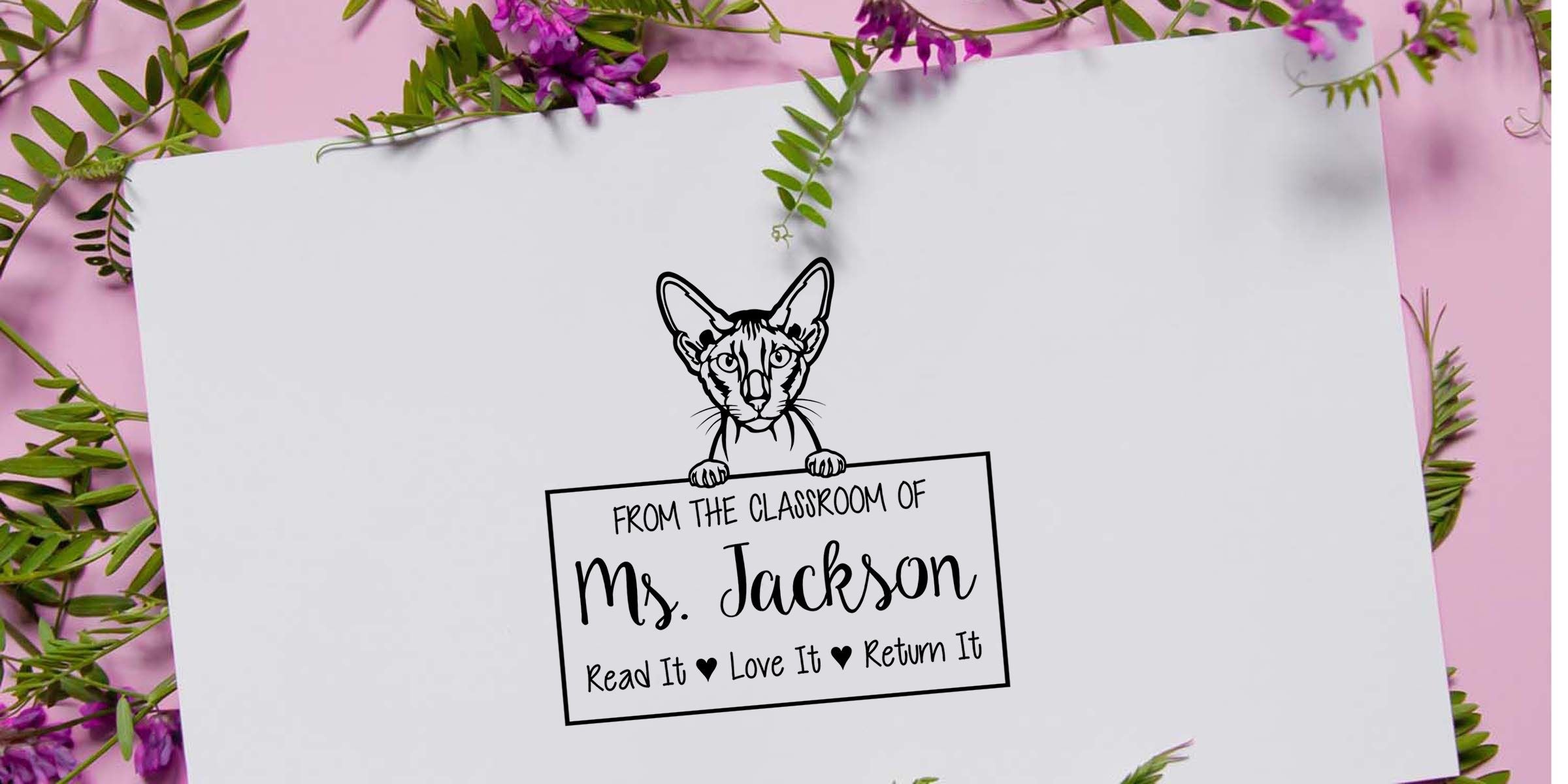 Personalized cat-themed classroom book label with “From the Classroom of Ms. Jackson” and “Read It Love It Return It” text on a white card surrounded by pink background, greenery, and purple flowers