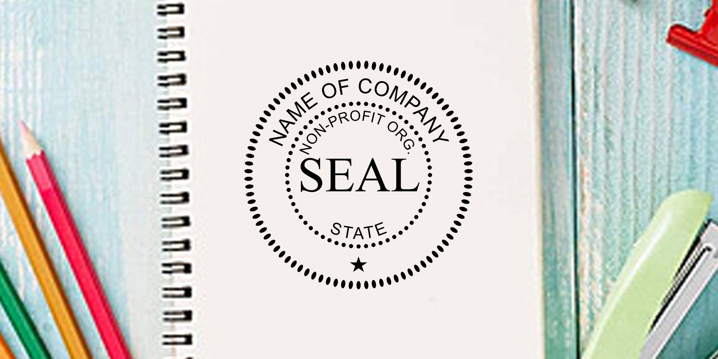 Notebook cover with non-profit organization seal stamp surrounded by colorful pencils and stationery on a desk
