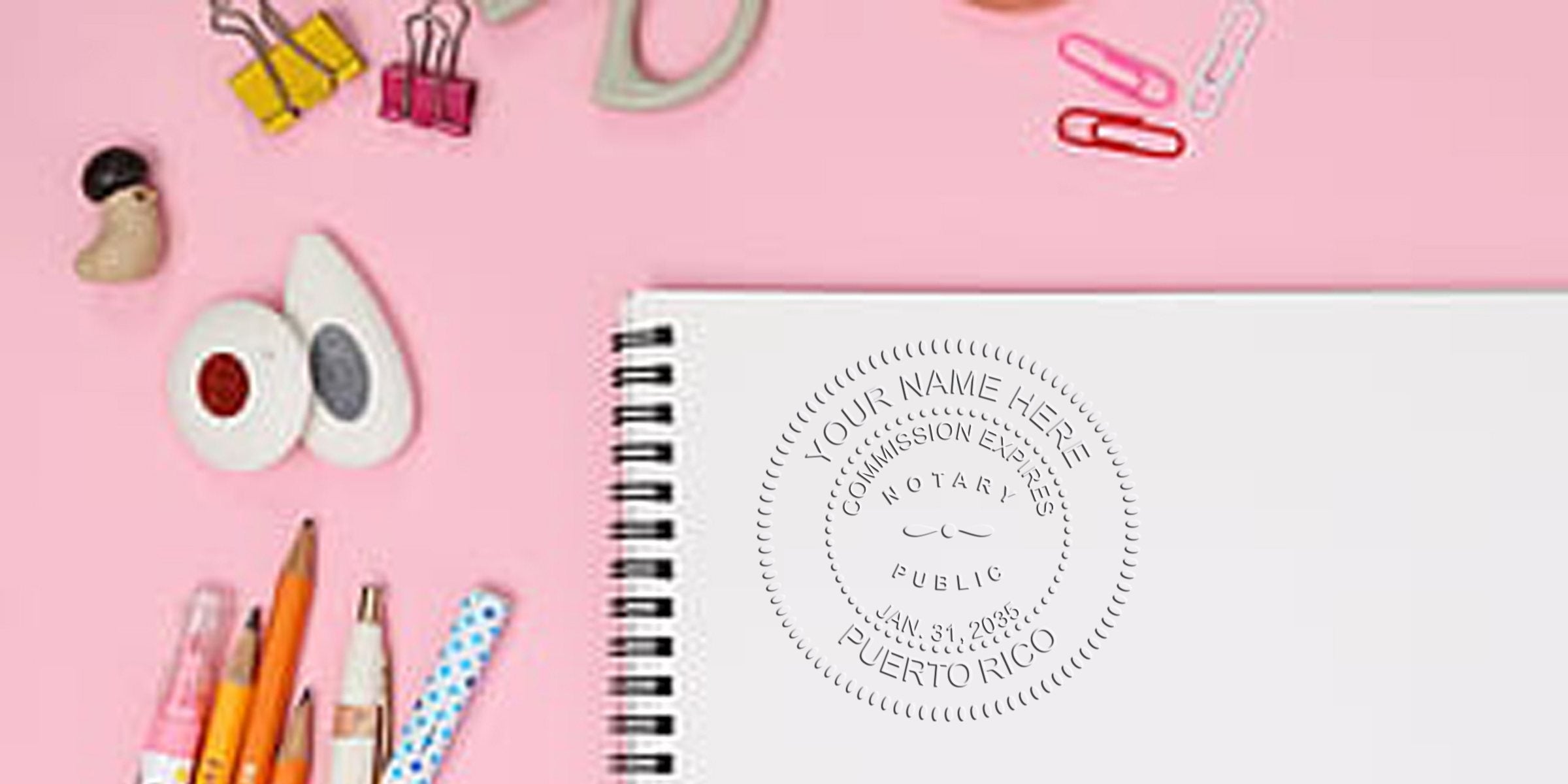 Puerto Rico notary stamps on white spiral notebook with office supplies on pink background, showcasing notary stamp deals for Puerto Rico services.