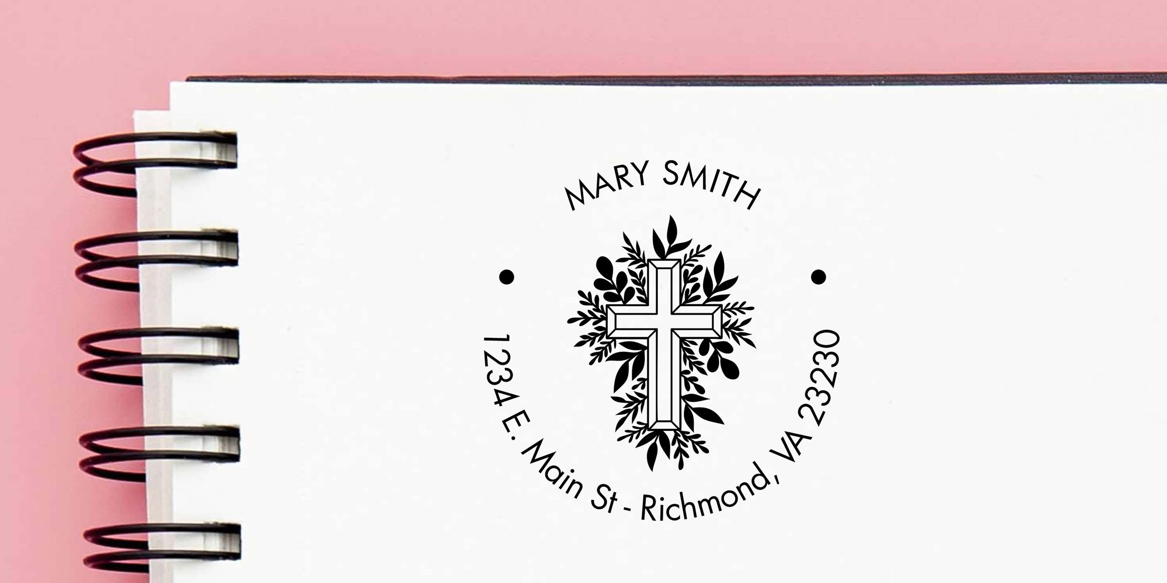 Customized spiral-bound notebook cover with floral cross logo, Mary Smith name, and Richmond, VA address on a pink background