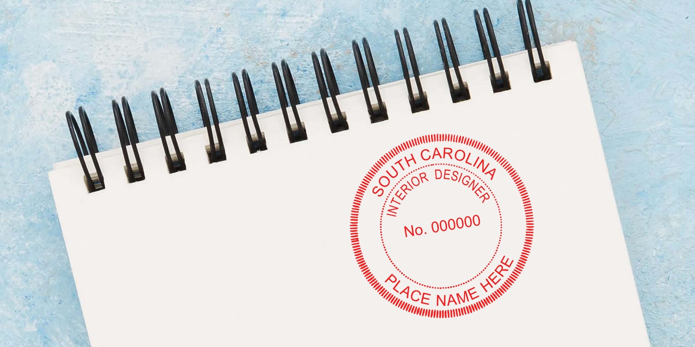 Spiral notebook with South Carolina interior designer stamp on blue textured background, showcasing South Carolina interior design laws and stamp regulations.