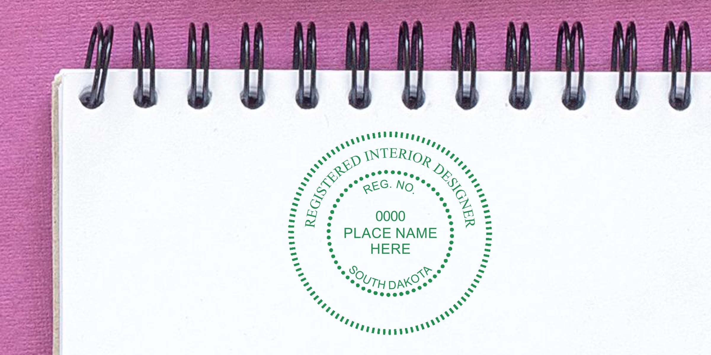 South Dakota interior designer stamp on white notebook with pink background, showcasing online interior designer certification.