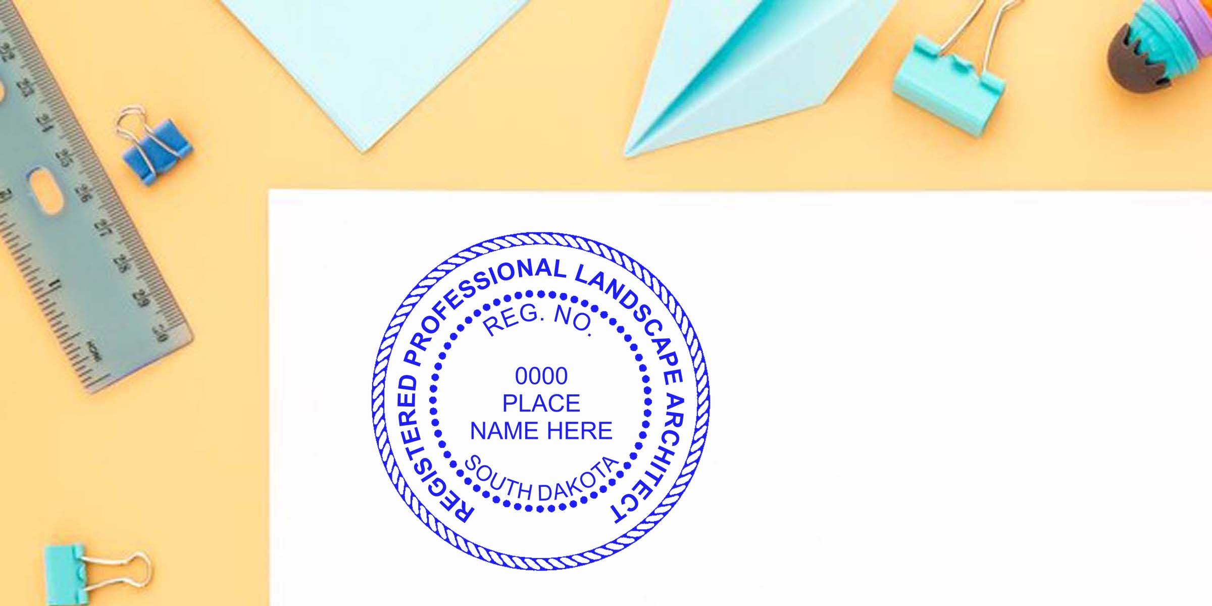Registered South Dakota landscape architect stamp on white paper with office supplies, adhering to landscape architect stamp guidelines.
