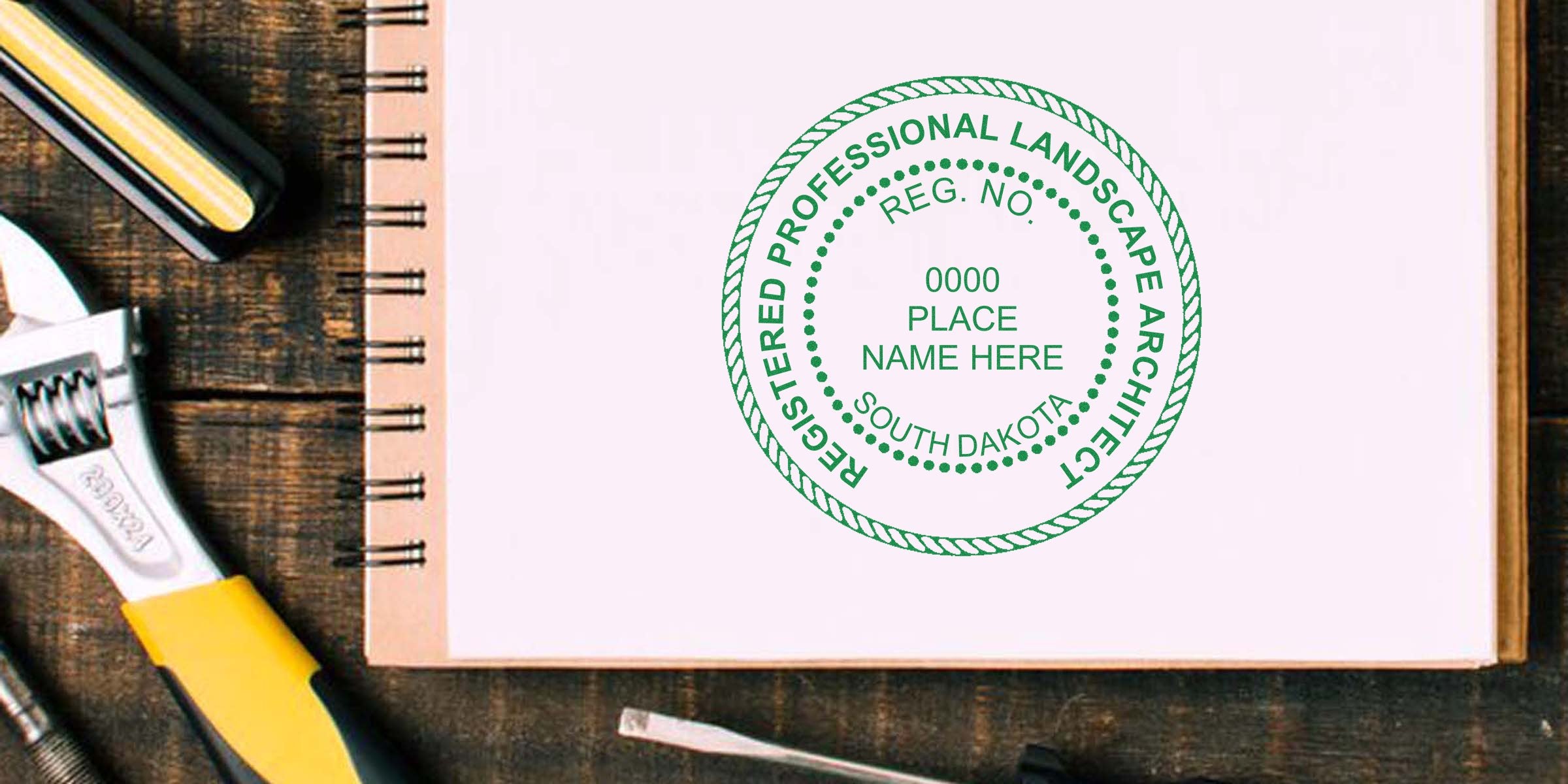 South Dakota landscape architect stamp on notebook with tools on wooden table, highlighting stamp requirements.
