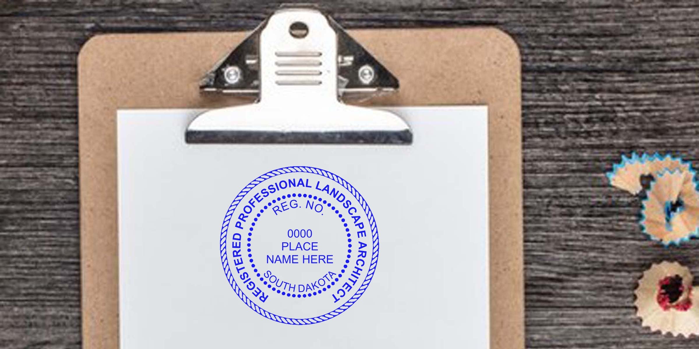 South Dakota landscape architect's registered seal stamped on clipboard paper with pencil shavings on a wooden table, showing the seal authentication process.