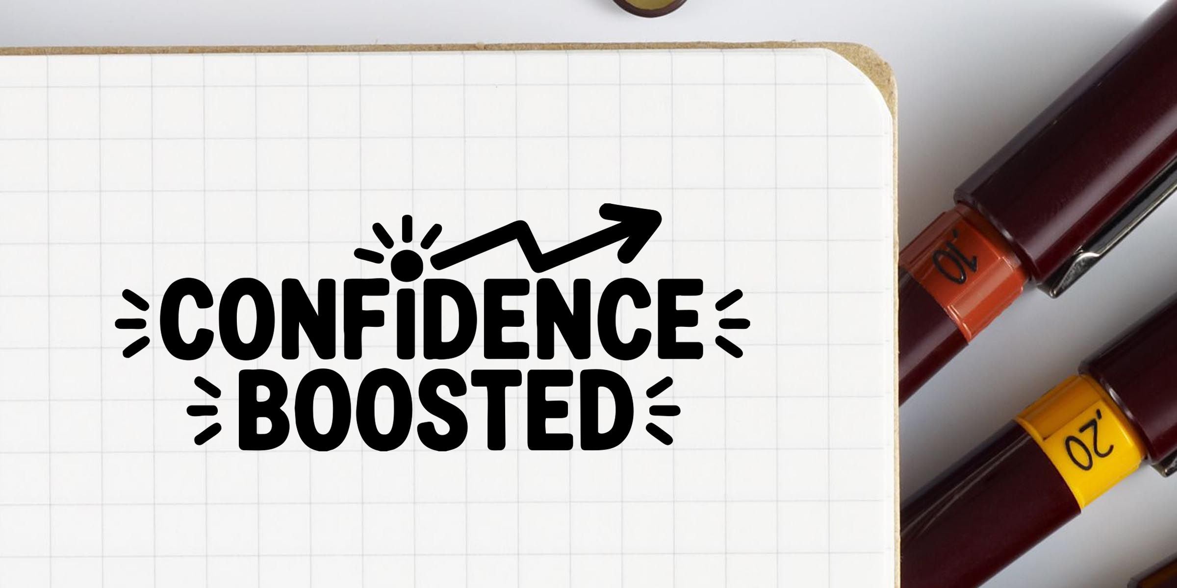 Confidence boosted text on a notebook page with colorful markers, personal growth and self-confidence concept