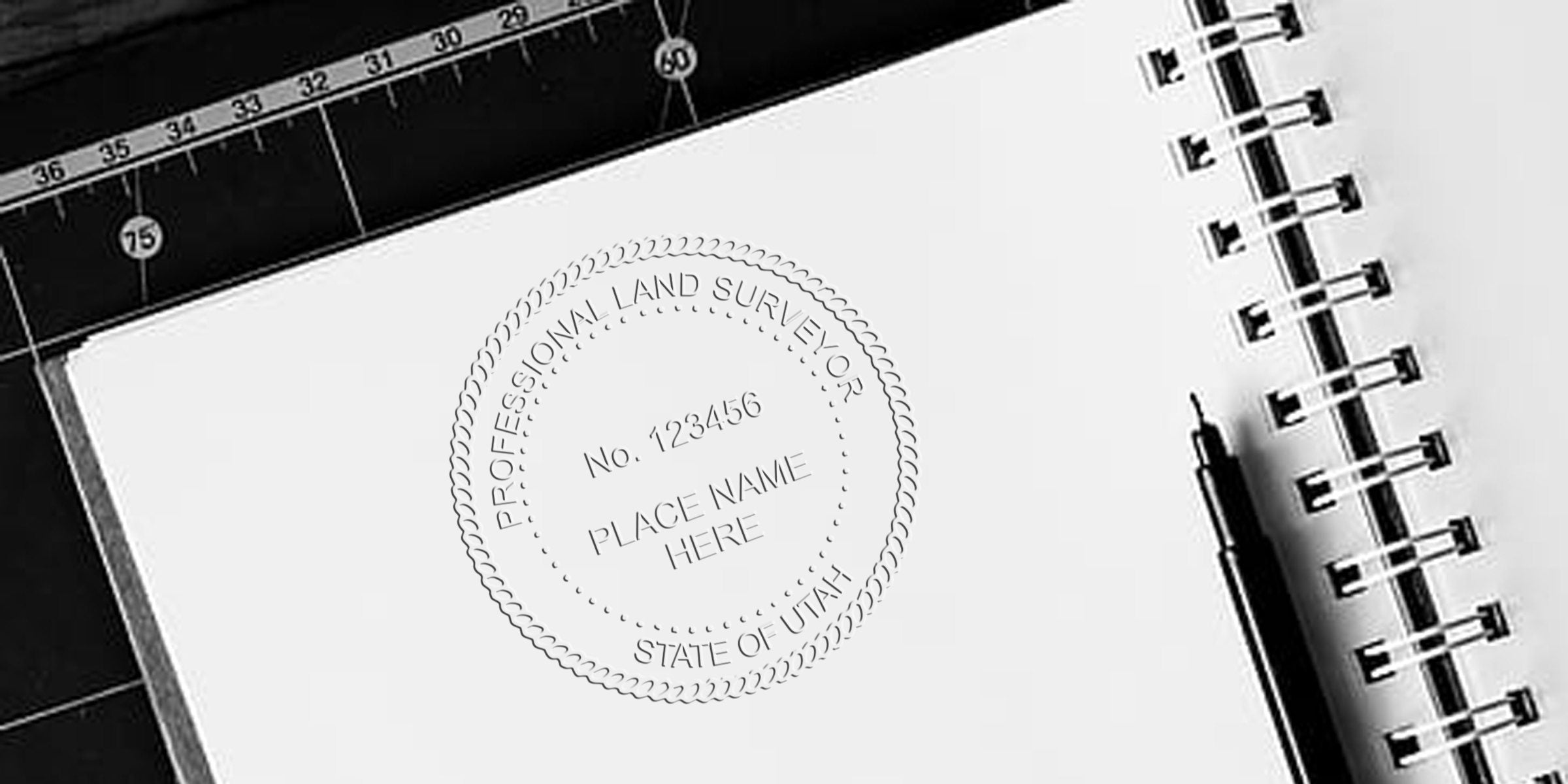Utah land surveyor stamp on notebook with ruler and pen, key tools for precise measurements and land surveyor licensing in Utah.