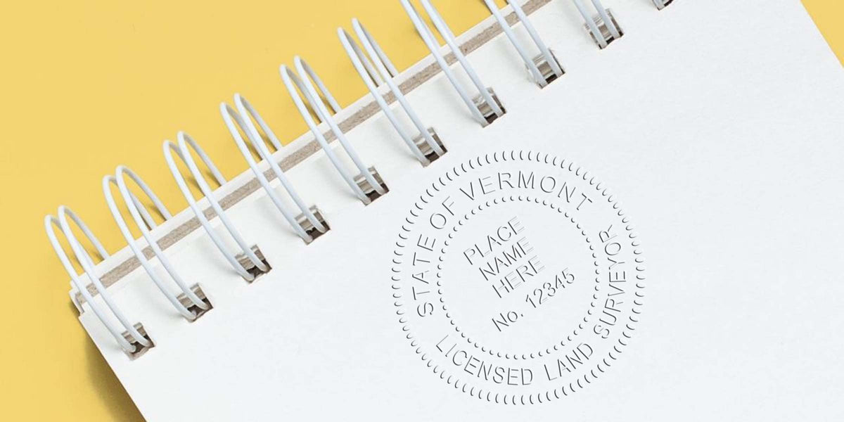 Spiral notebook with Vermont land surveyor embossed seal on yellow background, showcasing Vermont land surveyor stamp cost and budgeting.