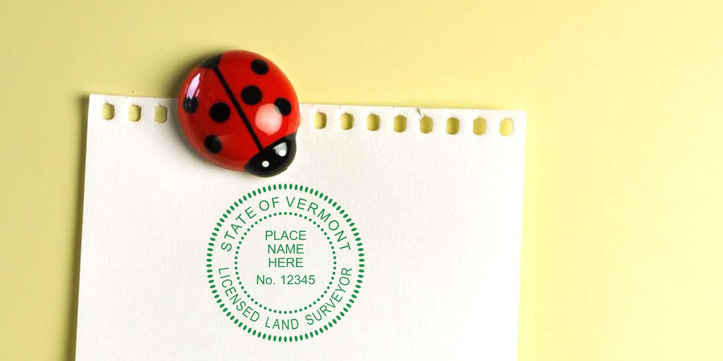 Ladybug magnet holds paper with Vermont land surveyor stamp on yellow background, highlighting land surveyor licensing requirements.