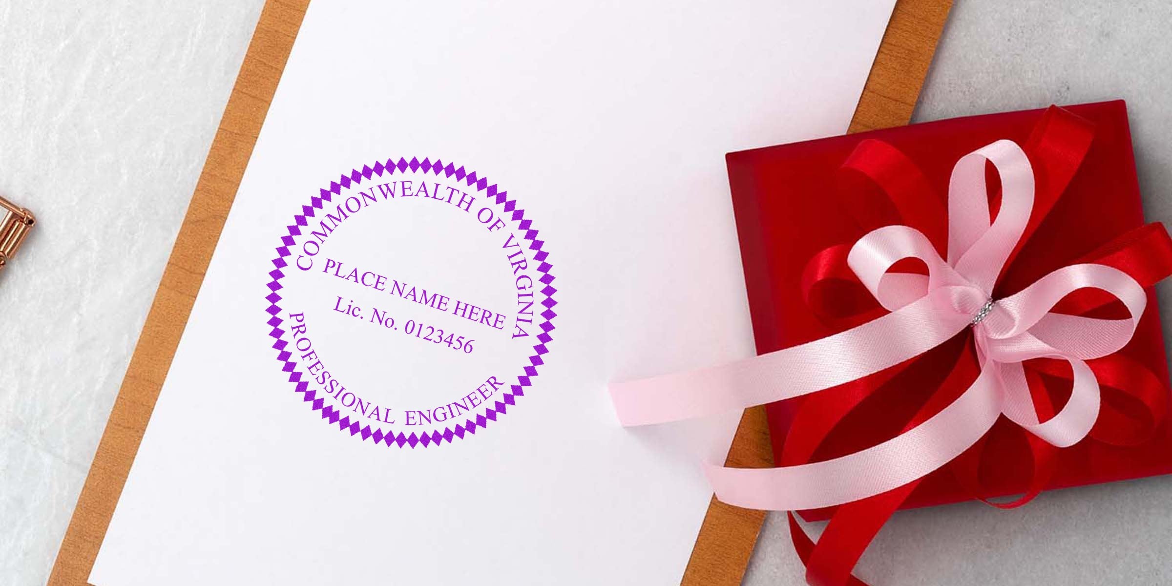 Virginia engineer stamp with a professional engineer seal on white paper, next to a red gift box tied with a pink ribbon, made by a quality engineer stamp maker.