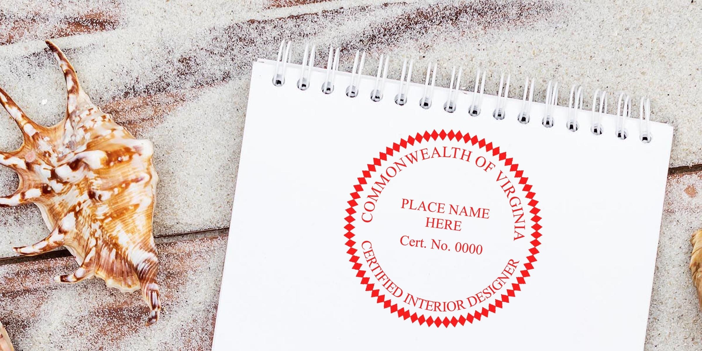 Virginia seal embosser on white notepad surrounded by seashells and design tools on a wooden surface.