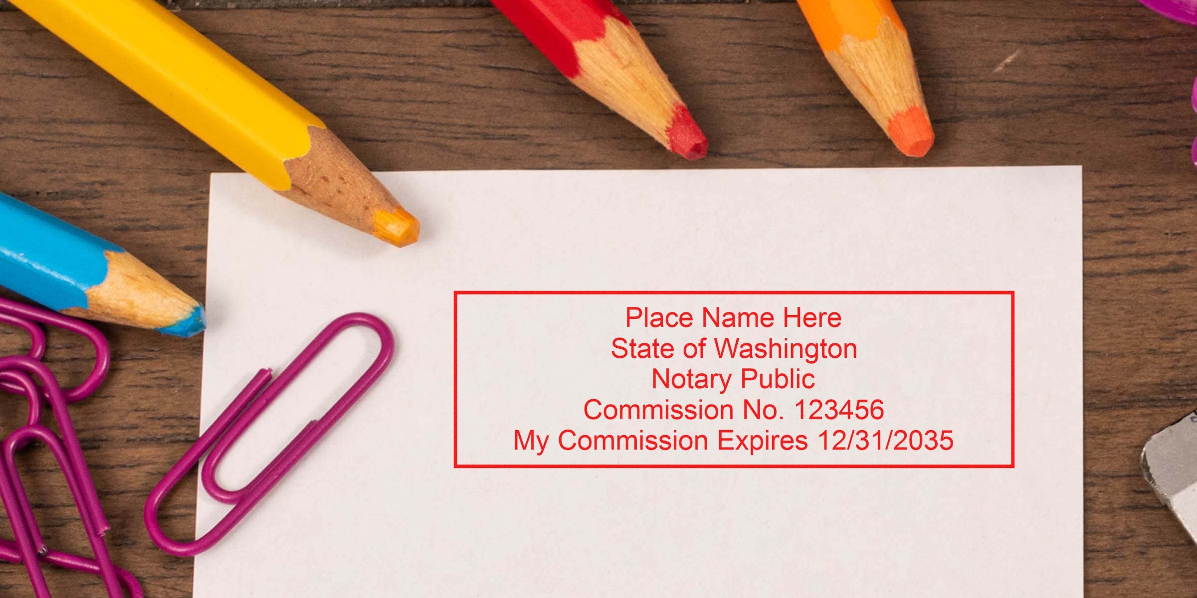 Red notary stamp on white paper with colored pencils and clips on a wooden desk, showing Washington notary commission details and highlighting top Washington notary products and essential supplies.