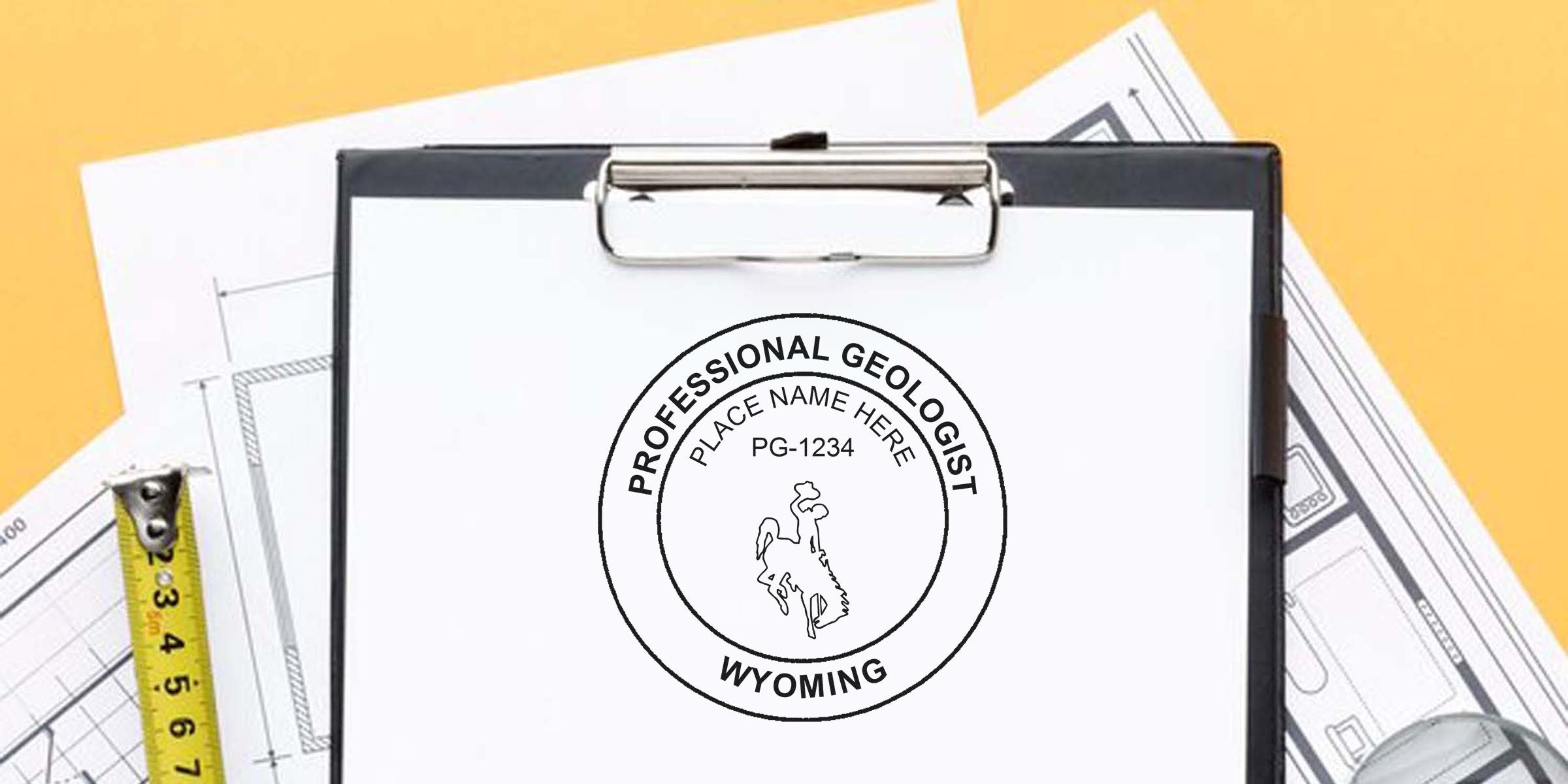 Wyoming Geologist Stamp on clipboard with blueprints and tape, showing the Professional Geologist Wyoming seal as part of the Essential Geologist Stamp Guide.