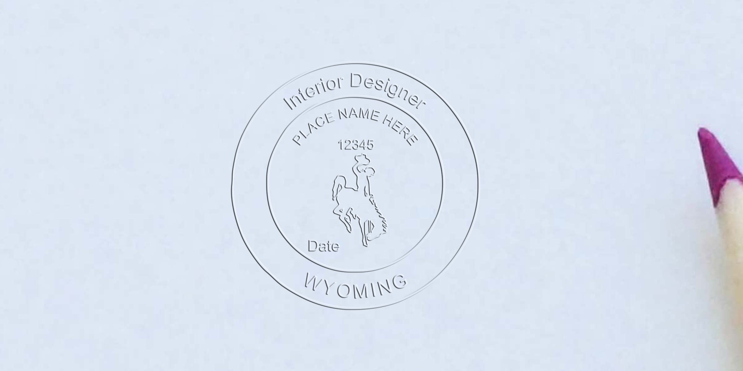 Embossed Wyoming interior designer seal on white paper with pink pencil tip, highlighting Wyoming interior design rules and seal requirements.