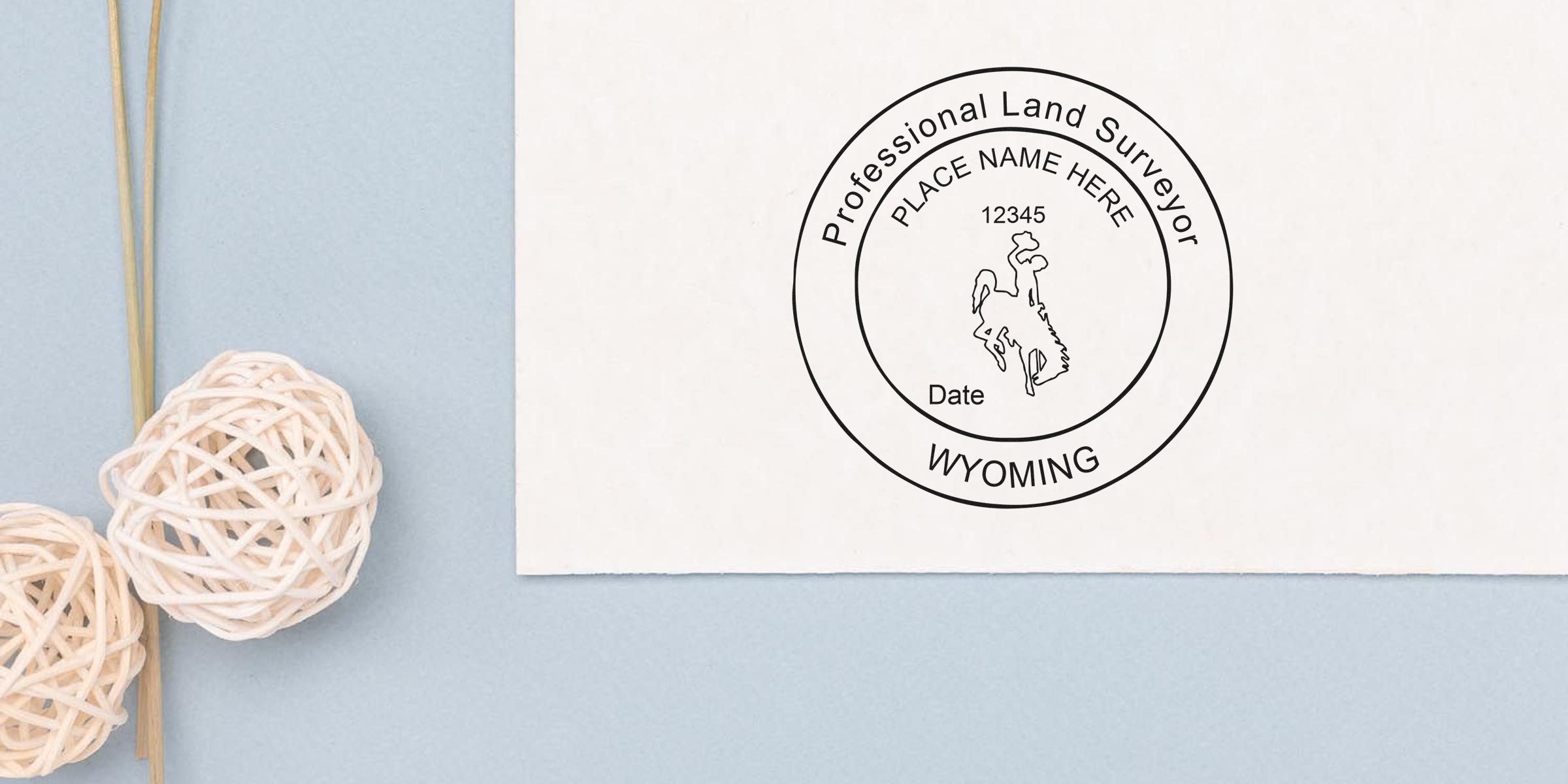 Wyoming land surveyor stamp on white paper with decorative wicker balls against a blue background, highlighting Wyoming land surveyor certification.