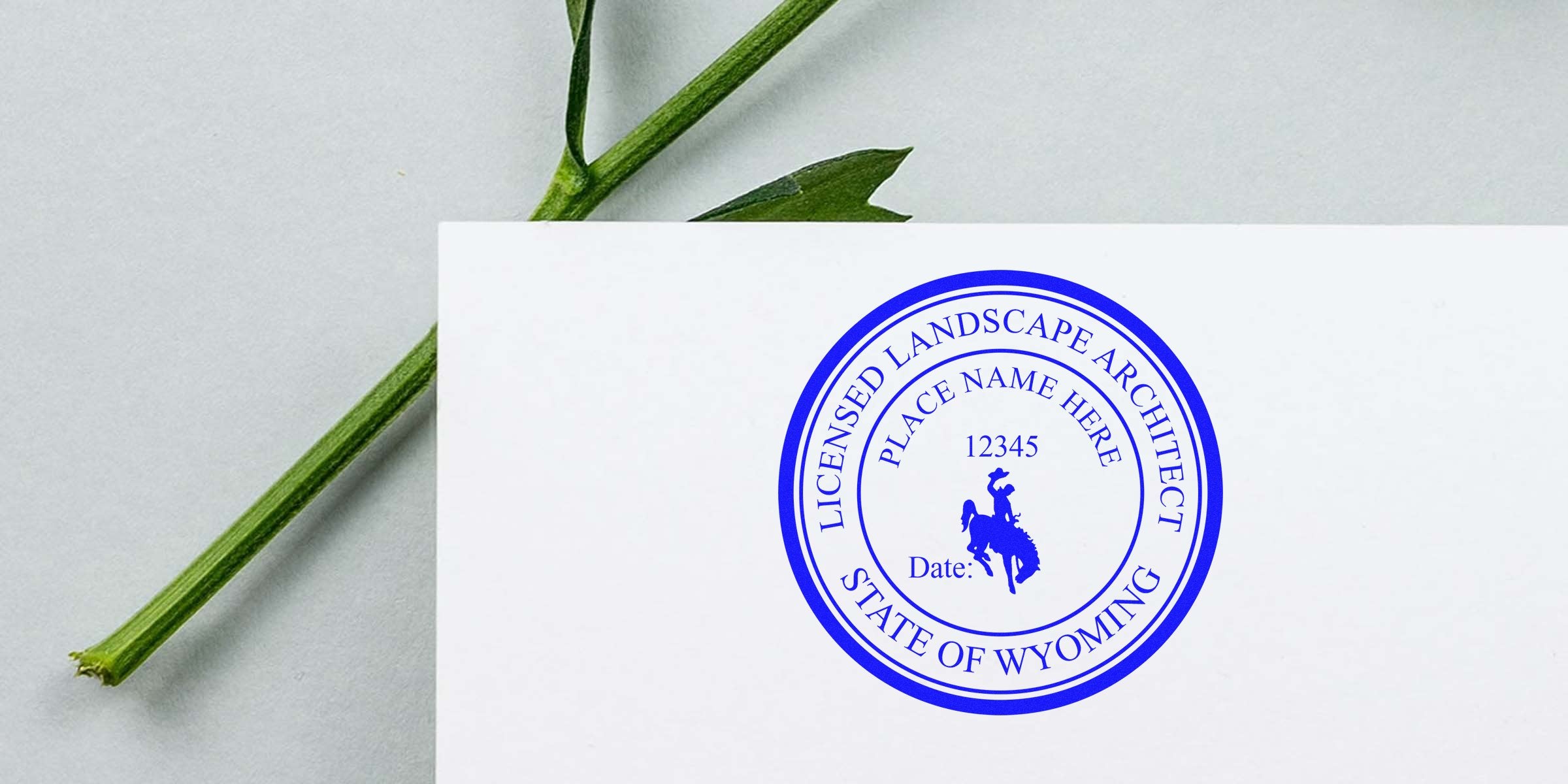 Wyoming landscape architect stamp with licensed seal on white paper and green plant stem, linked to online landscape architect certification.