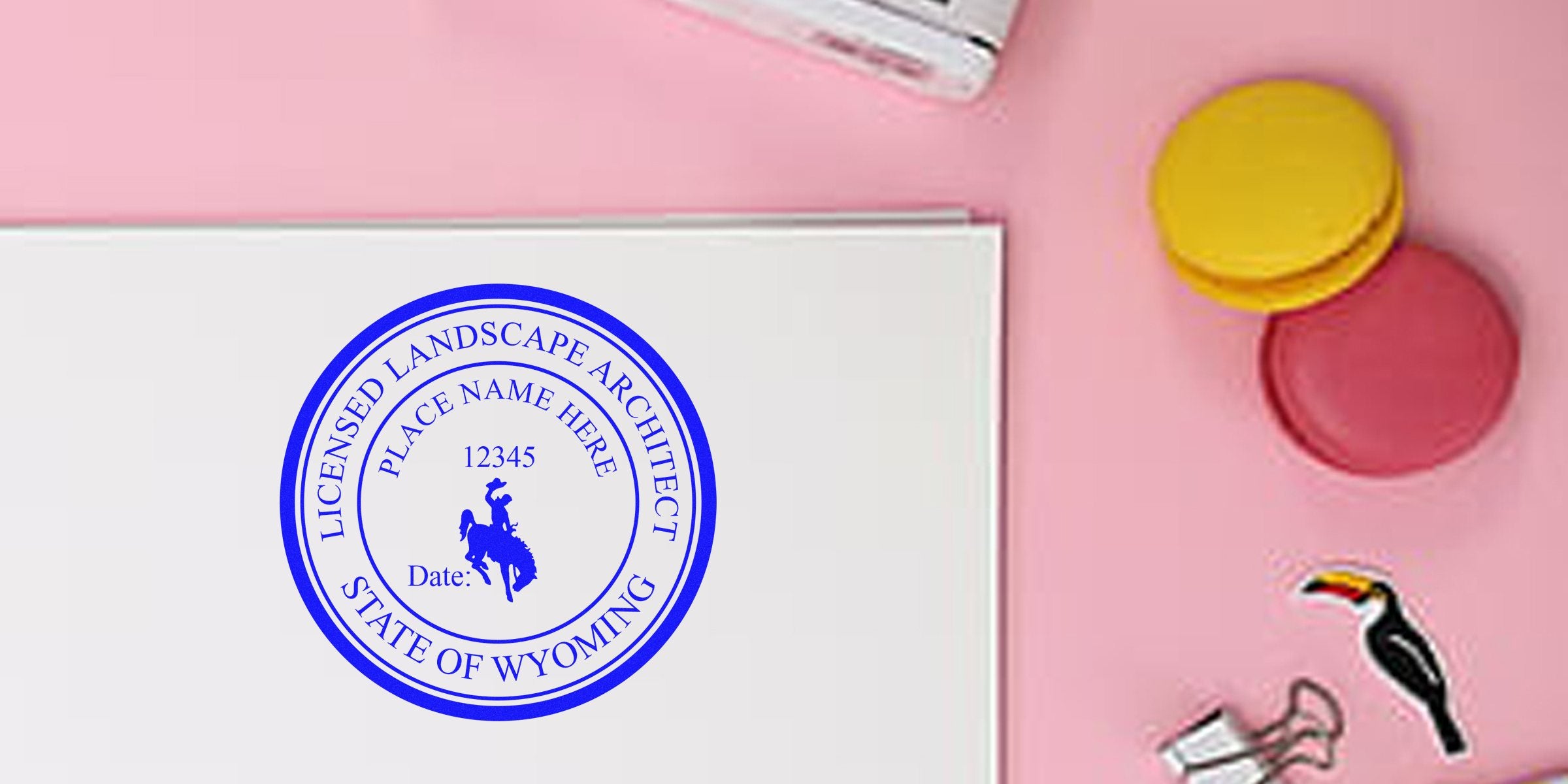 Licensed Landscape Architect Stamp Wyoming on white paper with colorful macarons and office supplies on pink background, showing Wyoming Board Landscape Architect seal.