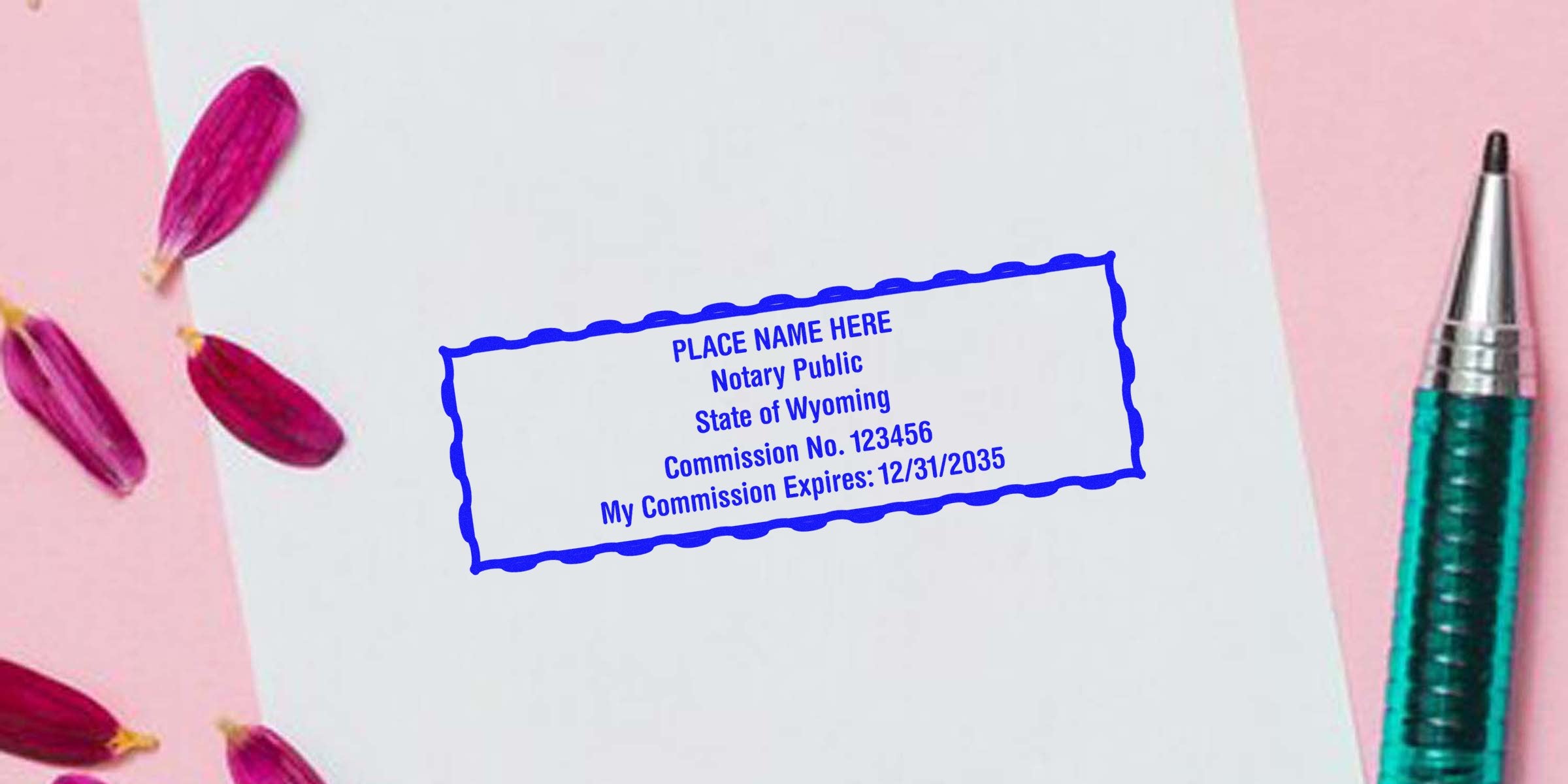 Wyoming notary public stamp with commission number and expiration date on white paper, alongside a pen, flower petals, and Wyoming notary kit with supplies.
