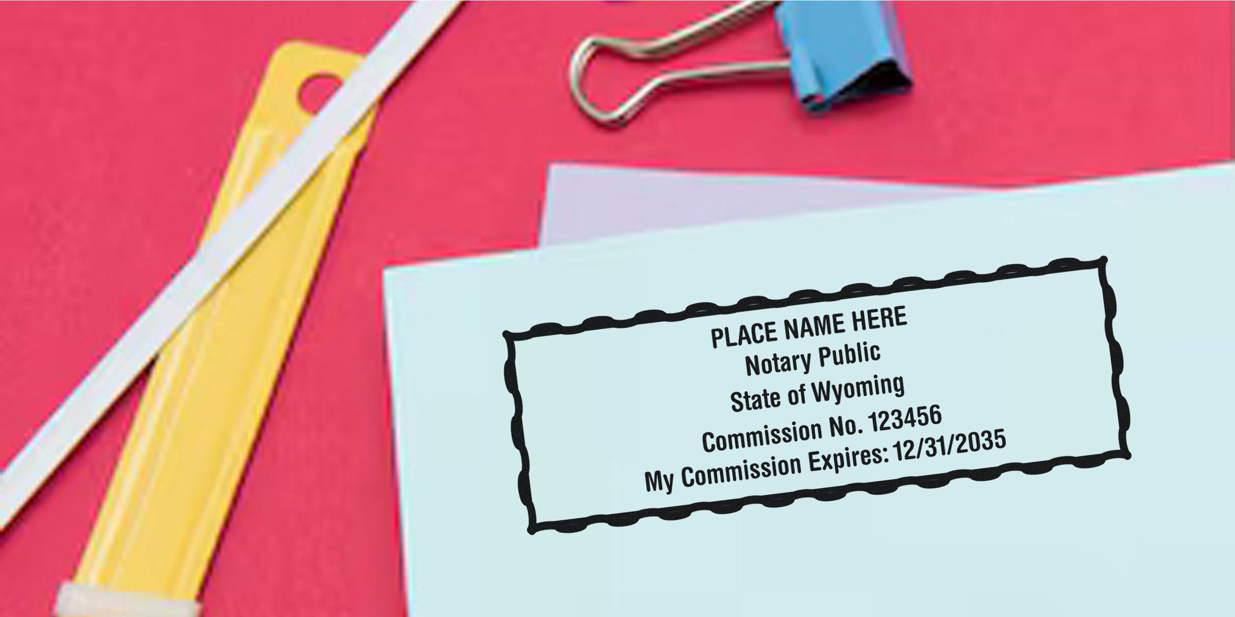 Custom Wyoming notary stamp on blue paper with trusted Wyoming notary supplies and office items on a red background.