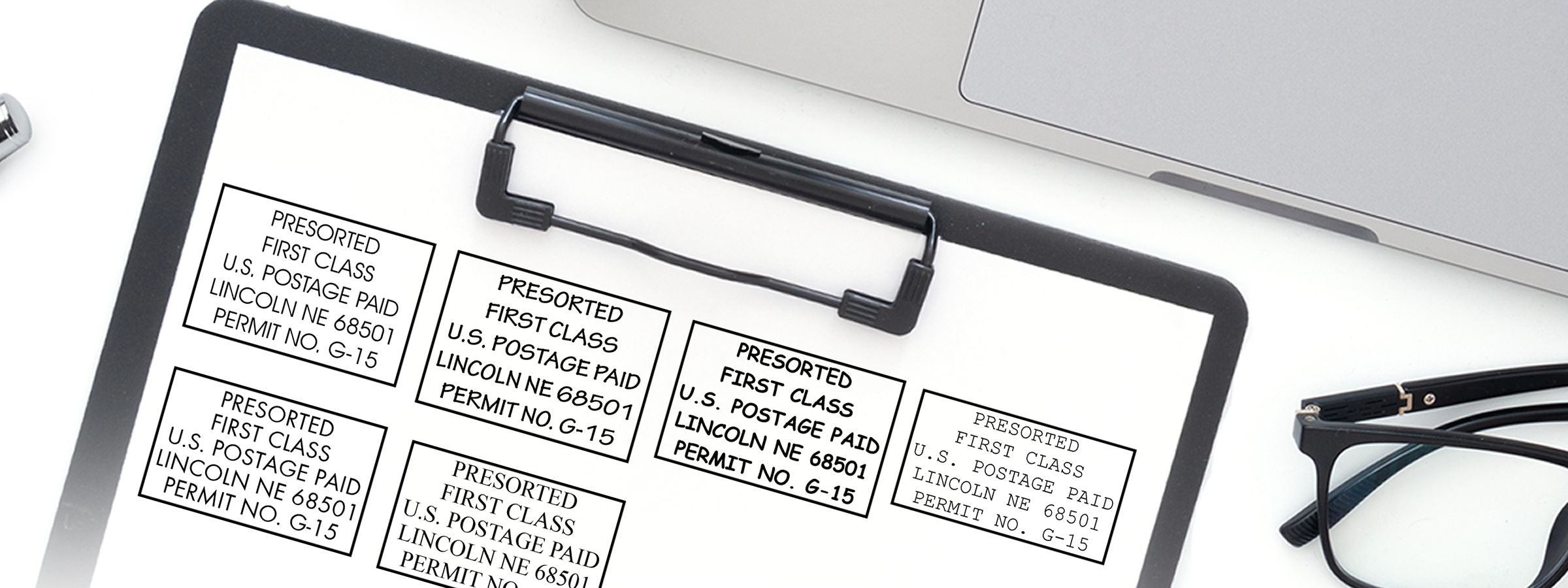 White sheet with six Presorted First Class U.S. Postage Paid labels beside a laptop and glasses, featuring Bulk Mail and Indicia Stamps.
